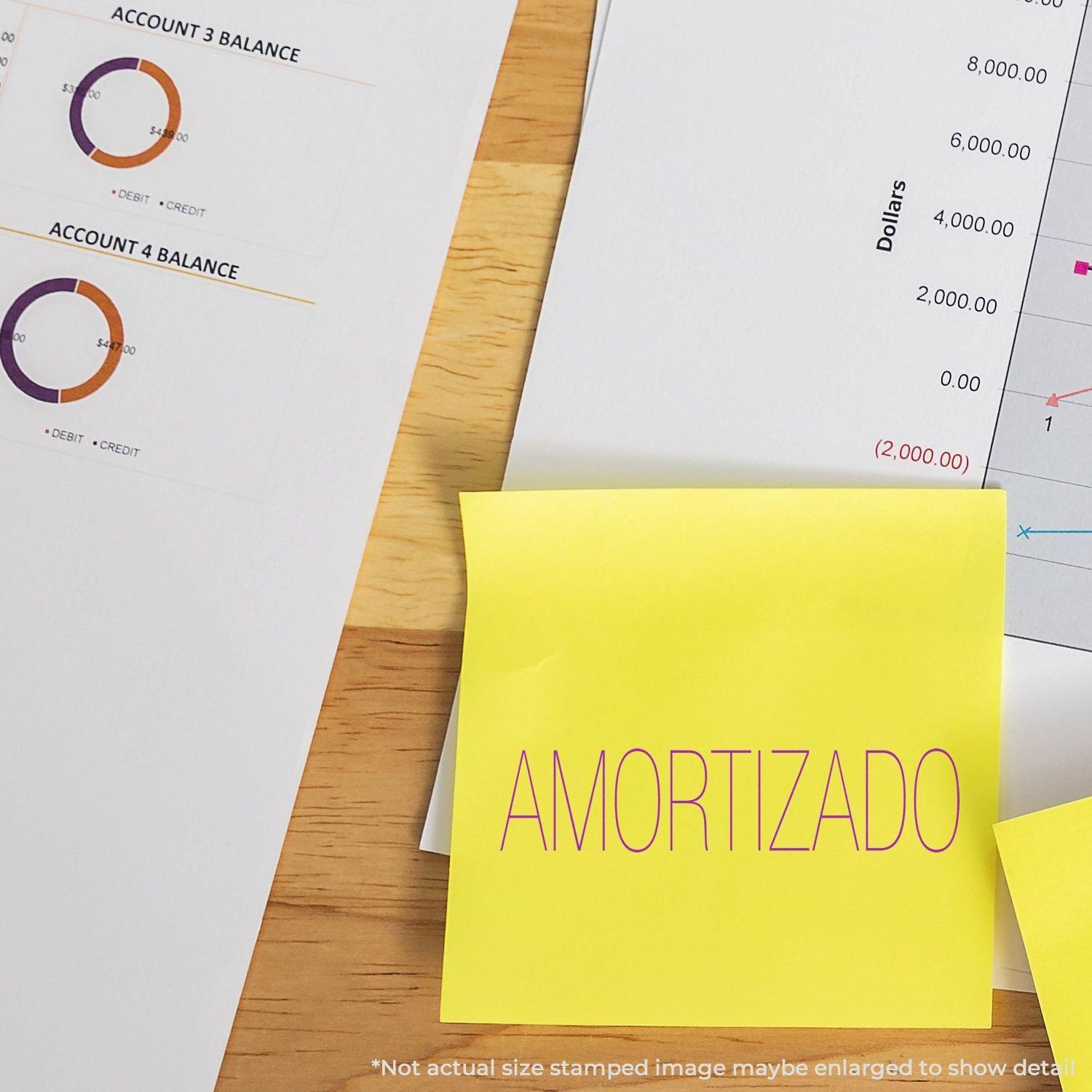 Yellow sticky note with AMORTIZADO stamped using a Slim Pre-Inked Amortizado Stamp, next to financial documents and charts.