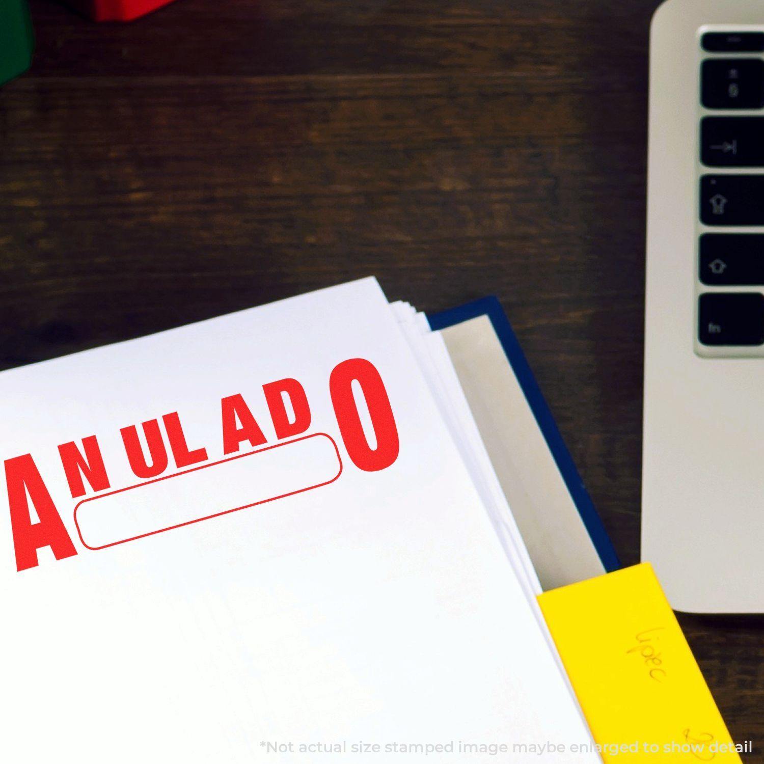 A document stamped with a red Anulado rubber stamp on a desk next to a laptop and a yellow sticky note.