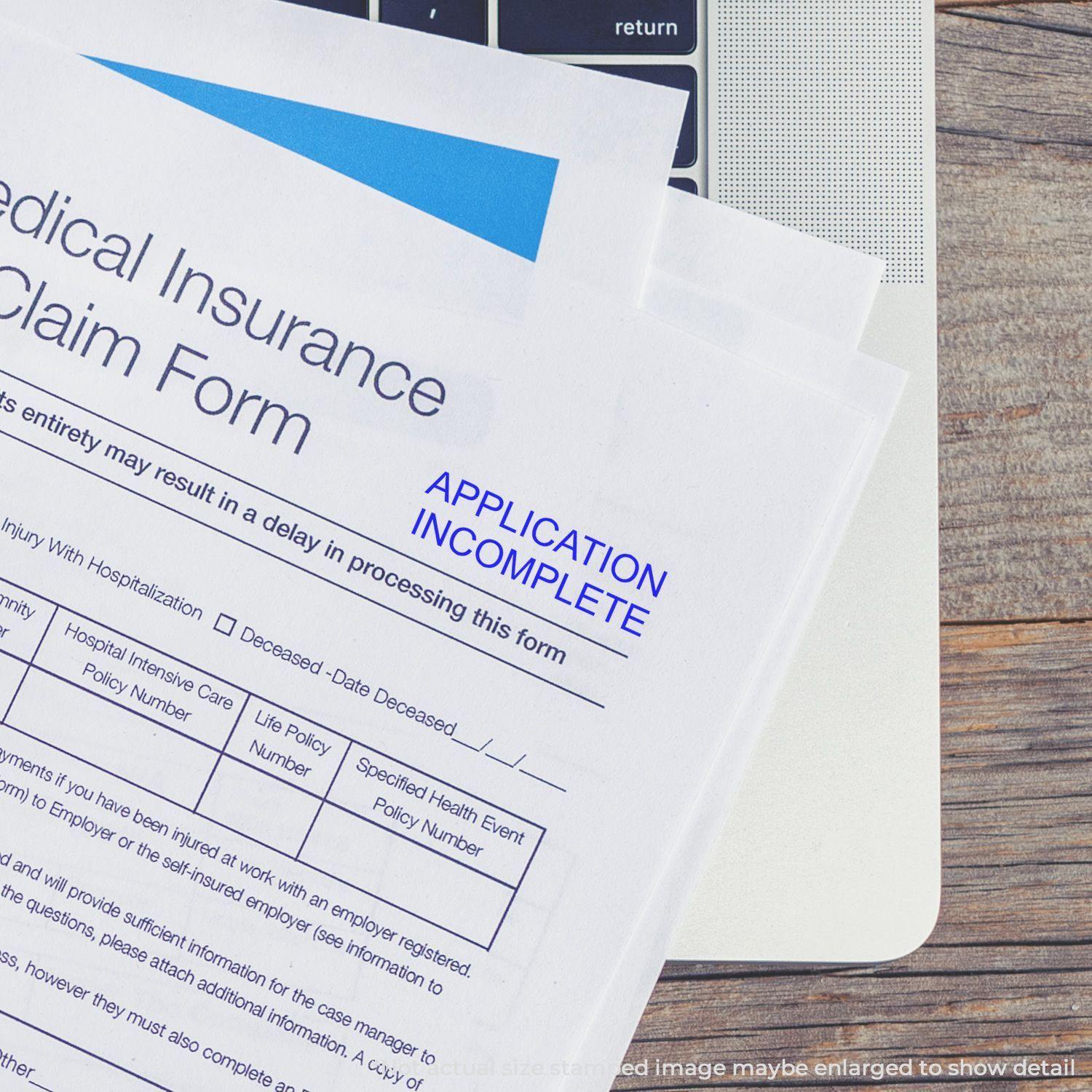 Medical insurance claim form stamped with APPLICATION INCOMPLETE using a Self Inking Application Incomplete Stamp, placed on a laptop.