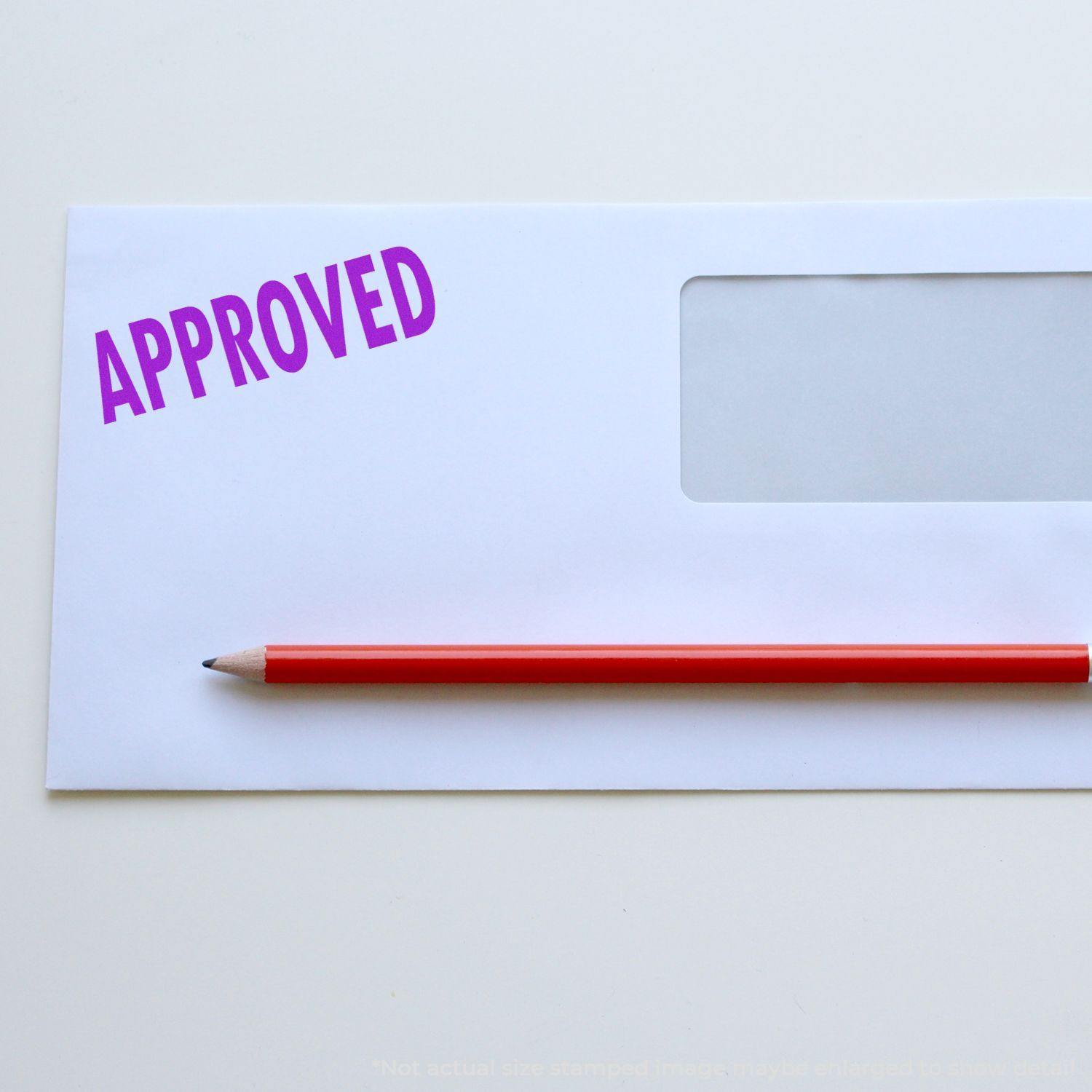 Large Pre-Inked Approved Stamp in purple ink on a white envelope with a red pencil placed diagonally across the envelope.