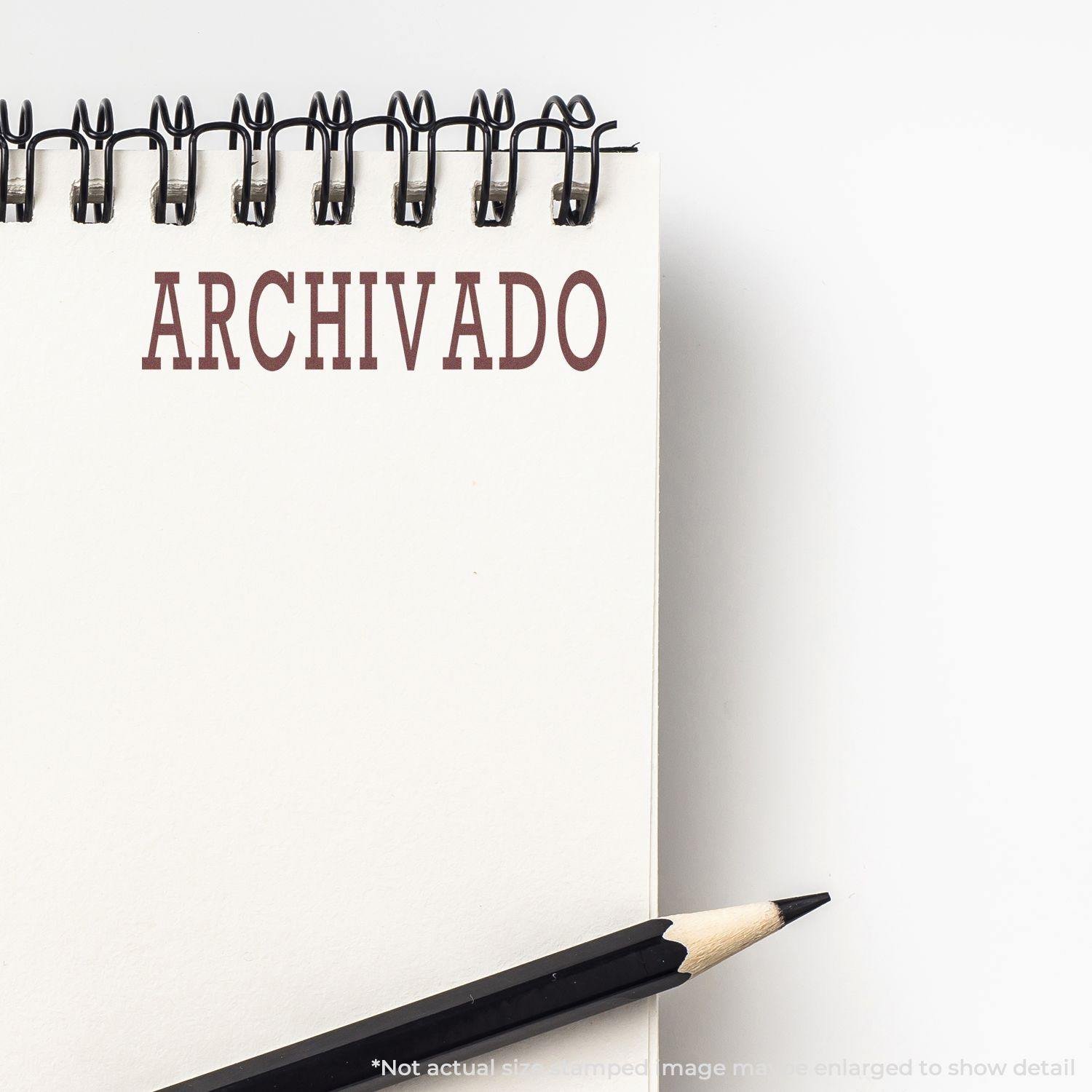 A notebook with the word ARCHIVADO stamped in brown ink using the Large Self Inking Archivado Stamp, with a pencil placed beside it.