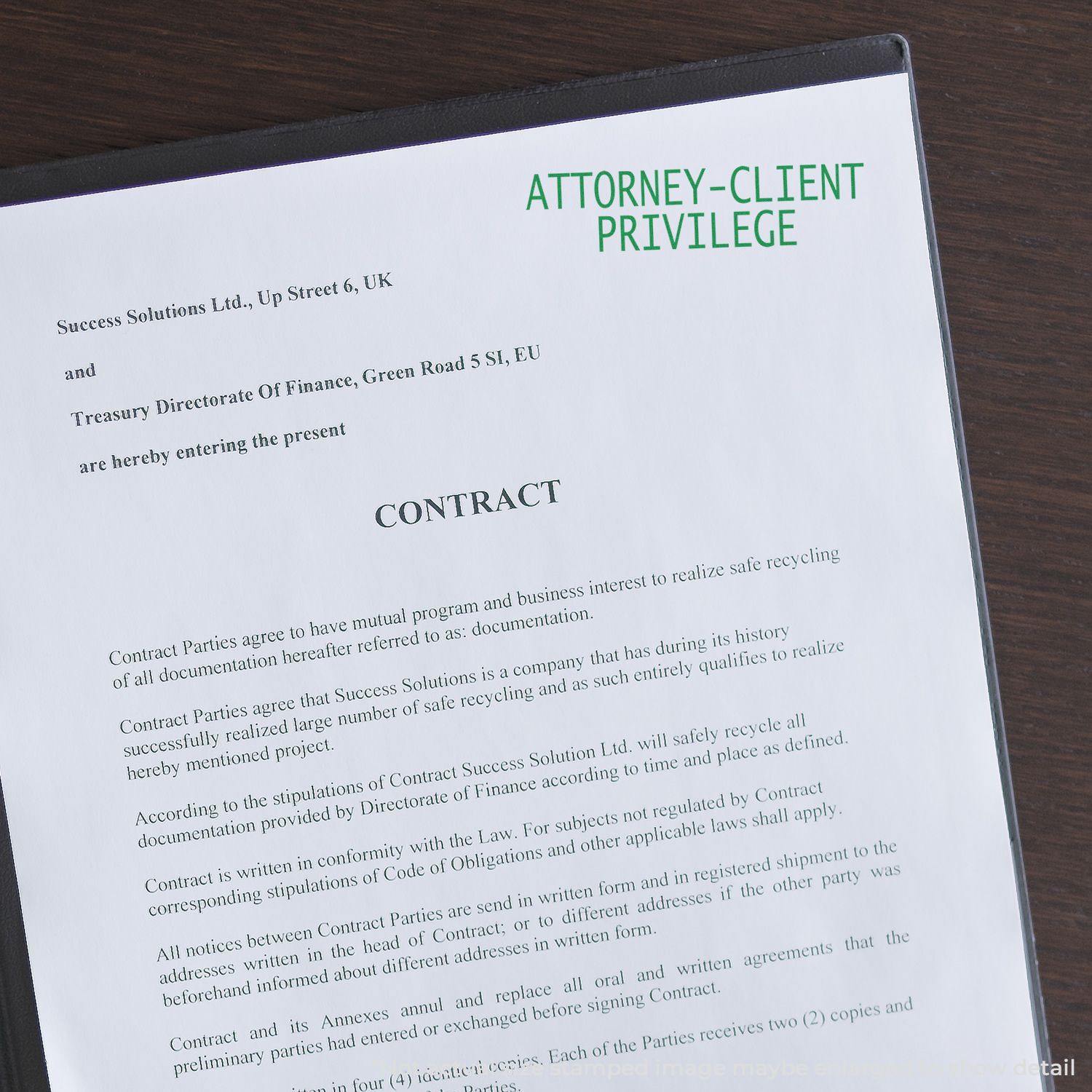 Attorney Client Privilege rubber stamp on a contract document with text and a binder on a wooden surface.