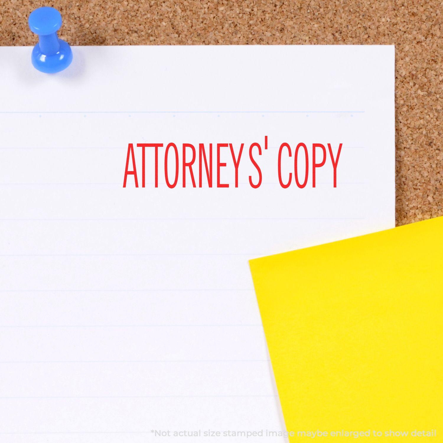 Attorneys' Copy rubber stamp in red ink on a white paper pinned to a corkboard with a blue pushpin and a yellow sticky note.