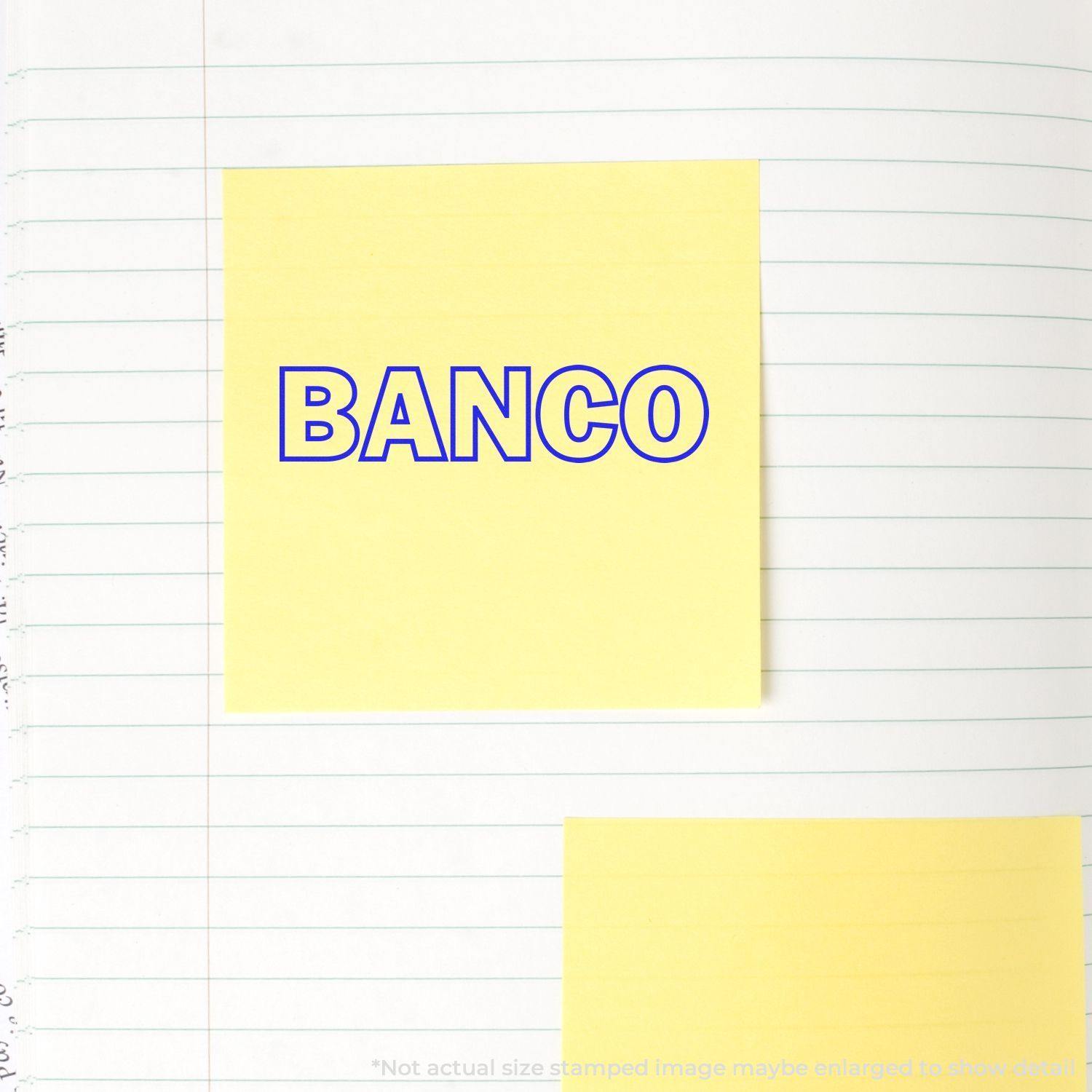 Yellow sticky note stamped with BANCO in blue ink using a Slim Pre-Inked Banco Stamp, placed on a lined notebook page.