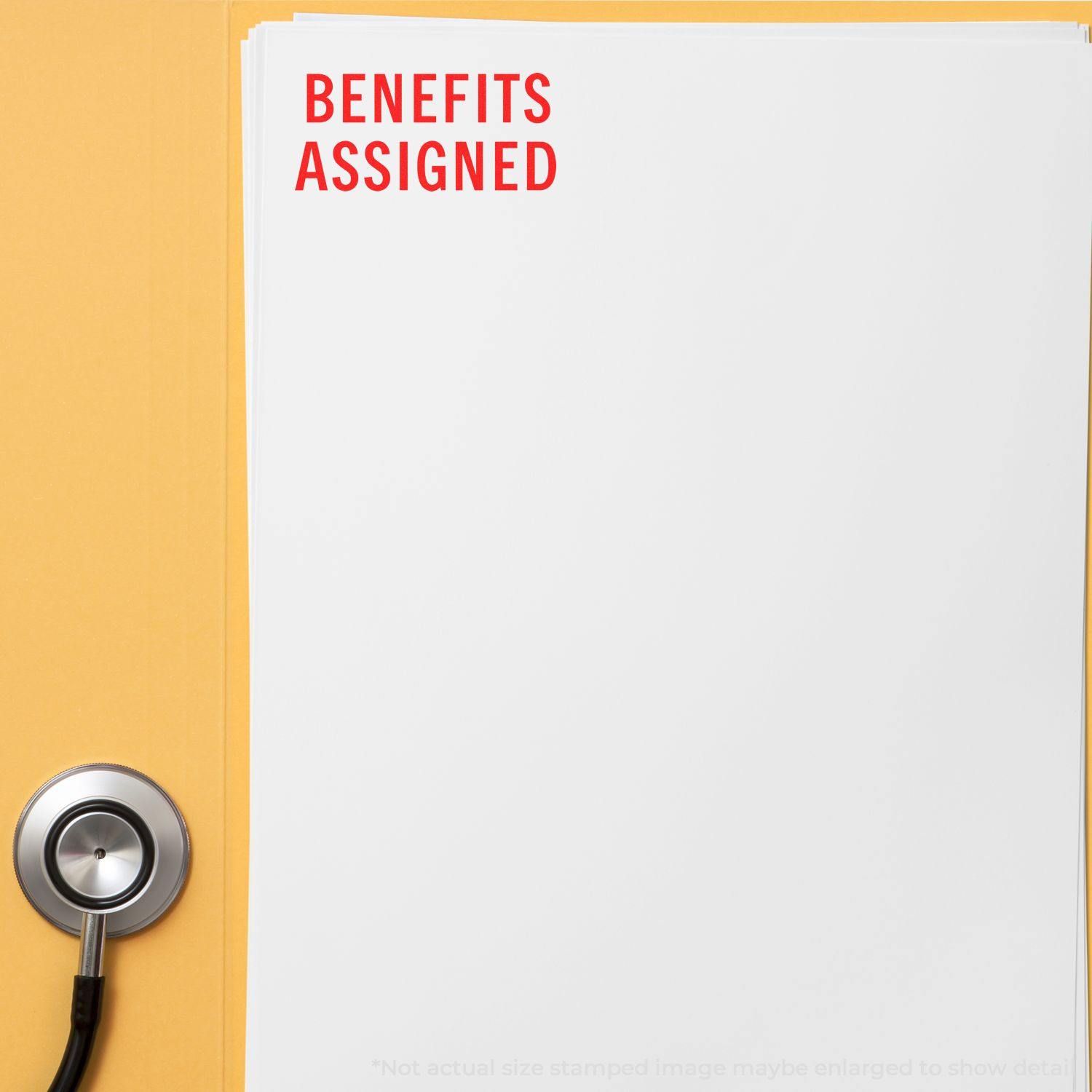 Benefits Assigned rubber stamp in red ink on a white document, placed on a yellow folder with a stethoscope nearby.