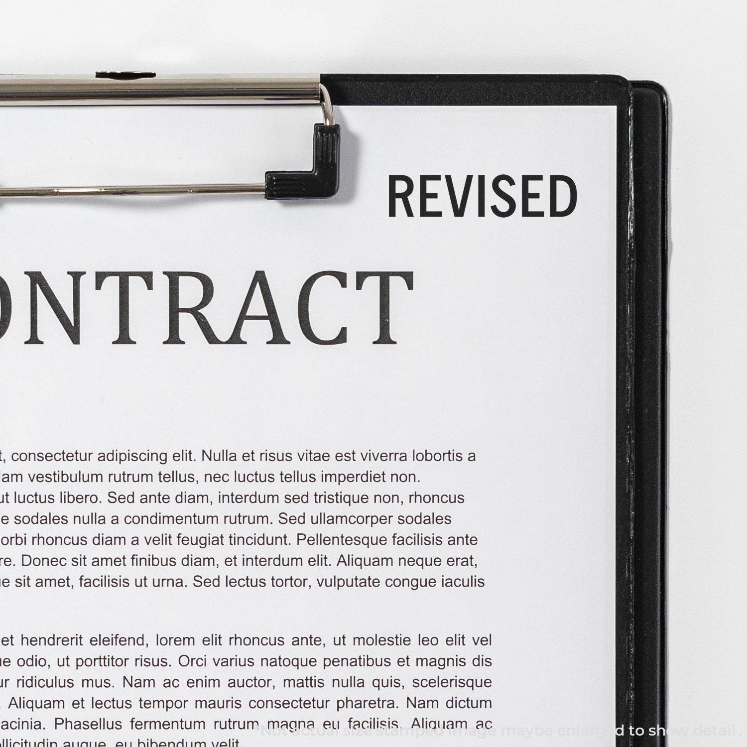 A clipboard holding a contract document with a black 'Revised' rubber stamp mark on the top right corner.