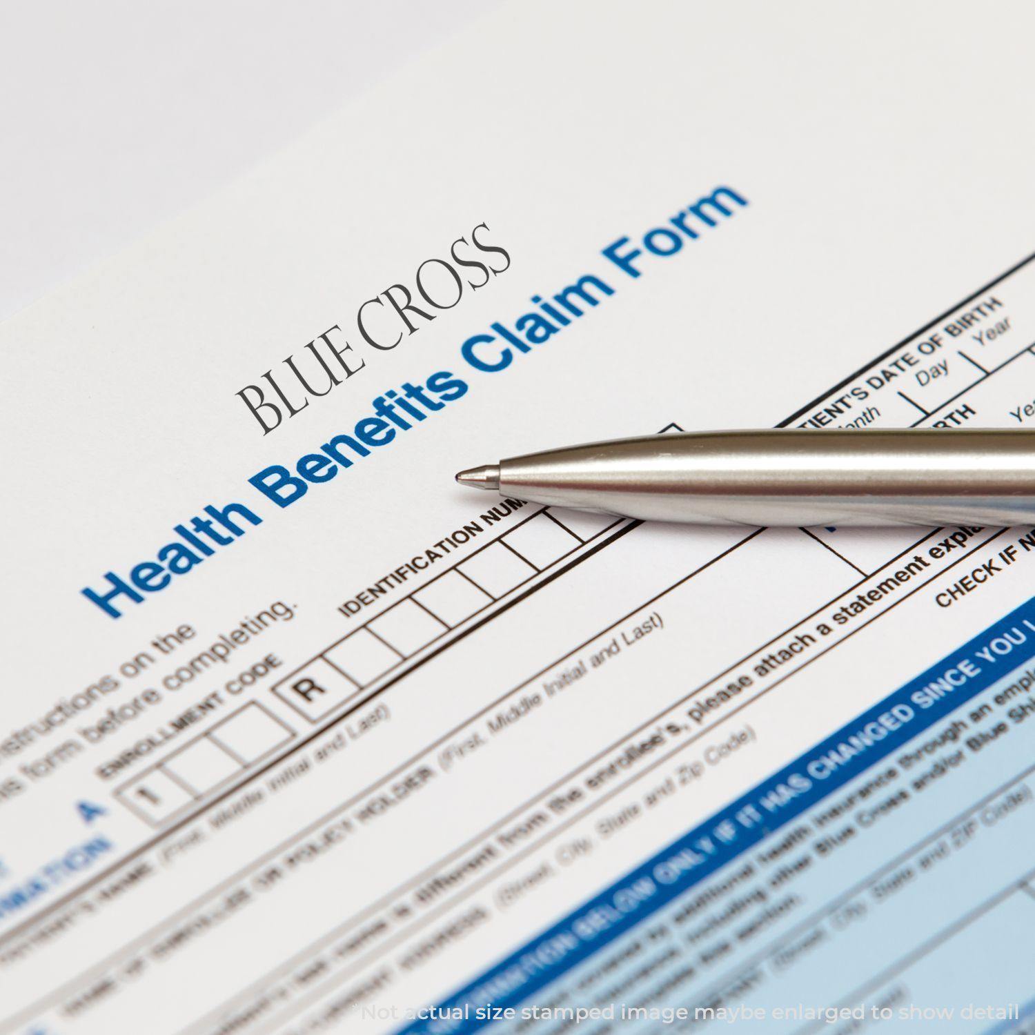 Slim Pre-Inked Blue Cross Stamp on a Health Benefits Claim Form with a pen placed on the form.