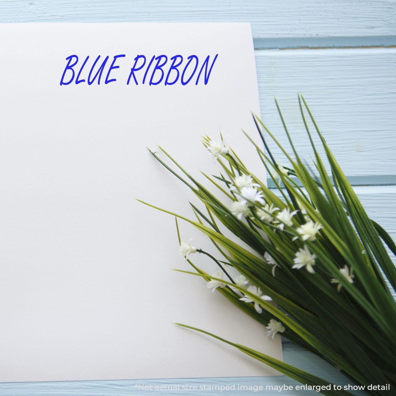 Large Self Inking Blue Ribbon Stamp used on white paper with a bouquet of white flowers on a light blue wooden background.