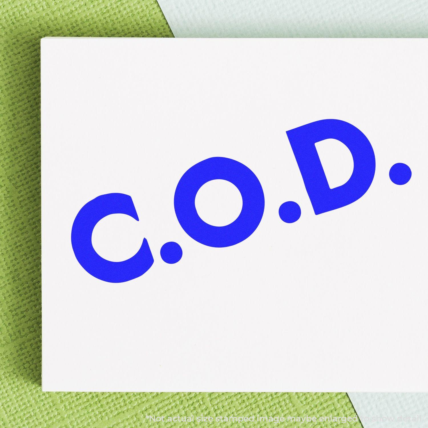 Bold COD rubber stamp impression in blue ink on white paper, placed on a green textured surface.