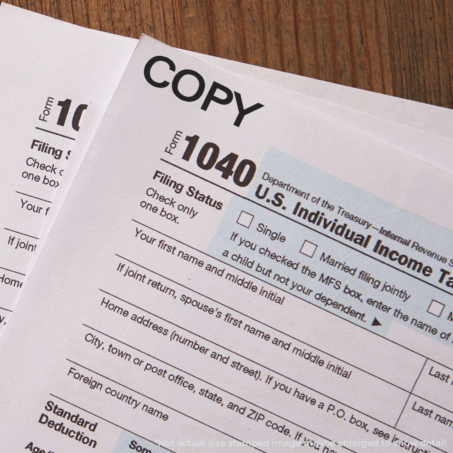 Two tax forms stamped with COPY using the Self Inking Bold Copy Stamp, placed on a wooden surface.