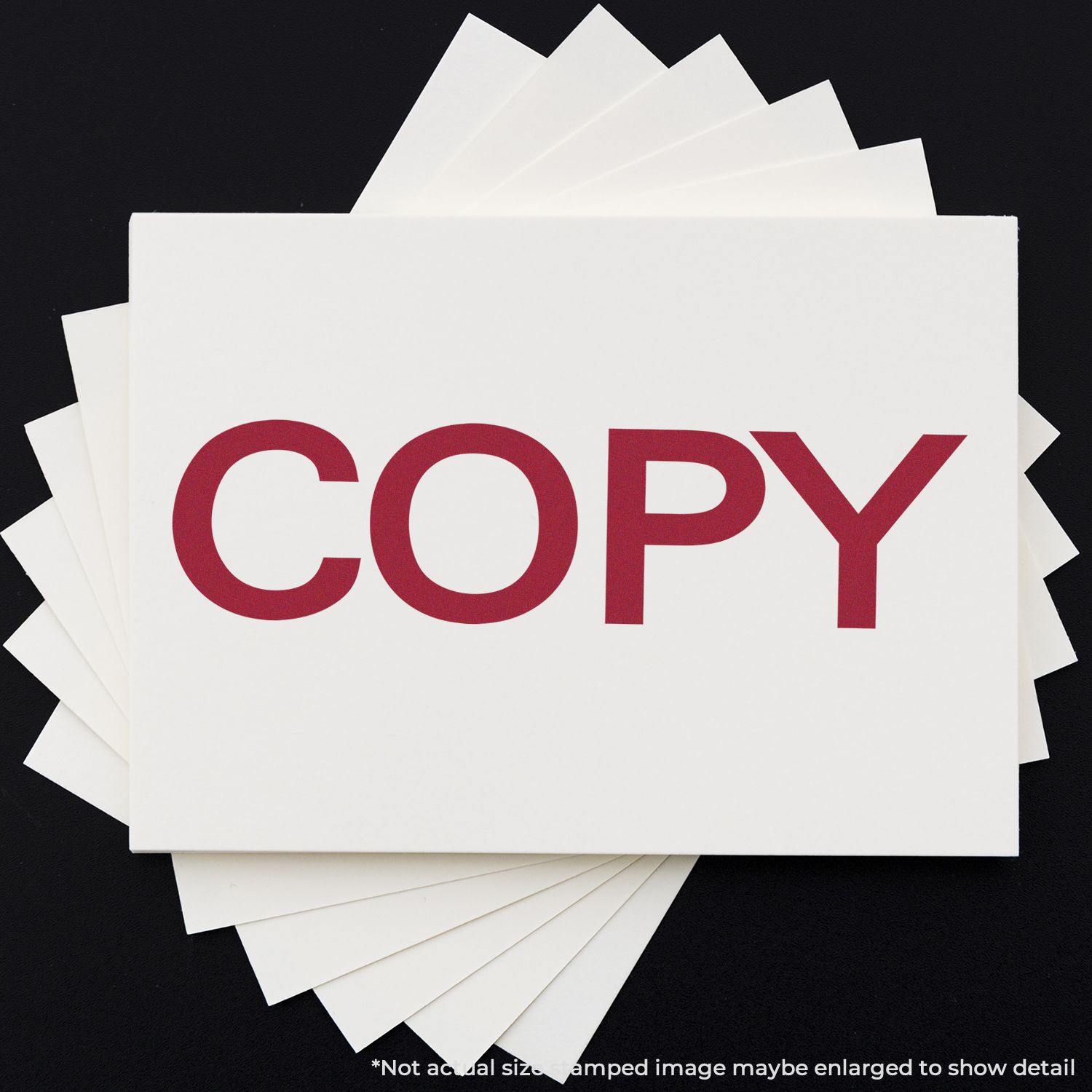 Bold Copy Rubber Stamp impression in red ink on a white card, with several white cards fanned out underneath on a black background.