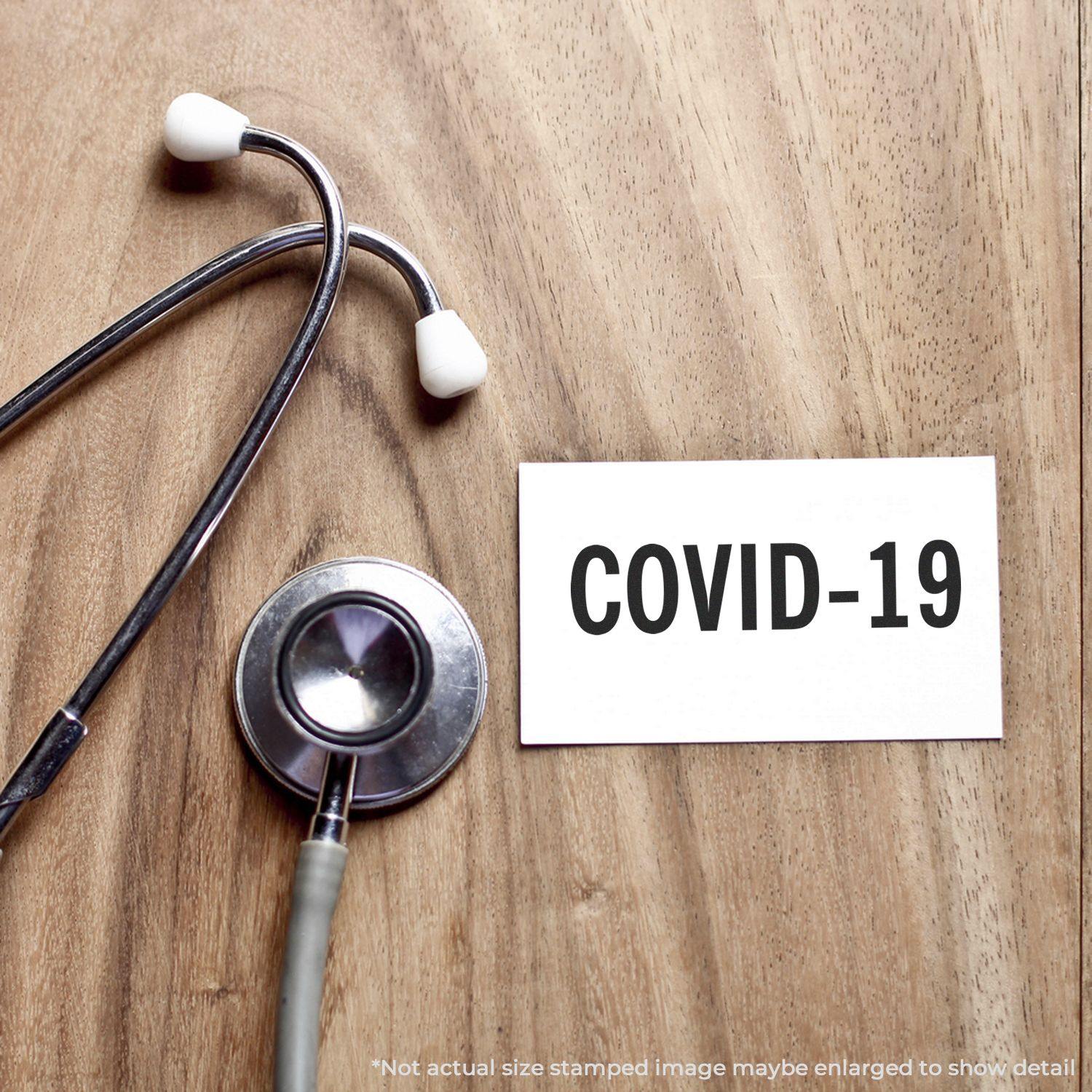 Stethoscope on wooden surface next to a card stamped with COVID-19 using a Slim Pre-Inked Bold Covid-19 Stamp.