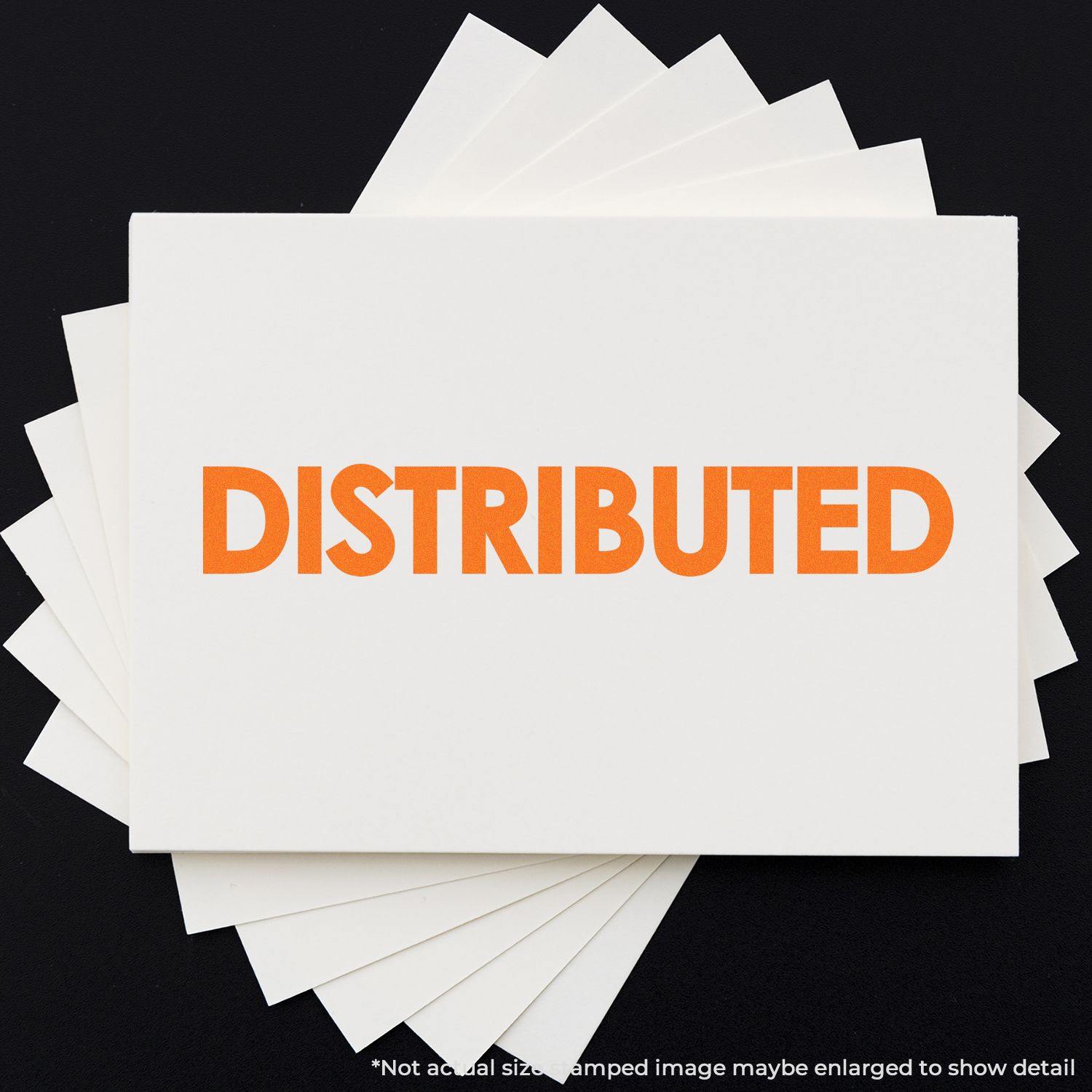 Bold Distributed Rubber Stamp in use, showing the word DISTRIBUTED in bright orange on a white card, with multiple cards underneath.