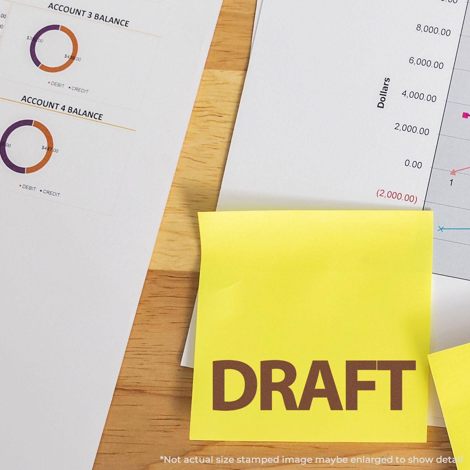 Large Self Inking Bold Draft Stamp used on a yellow sticky note, placed on a desk with financial documents and charts.