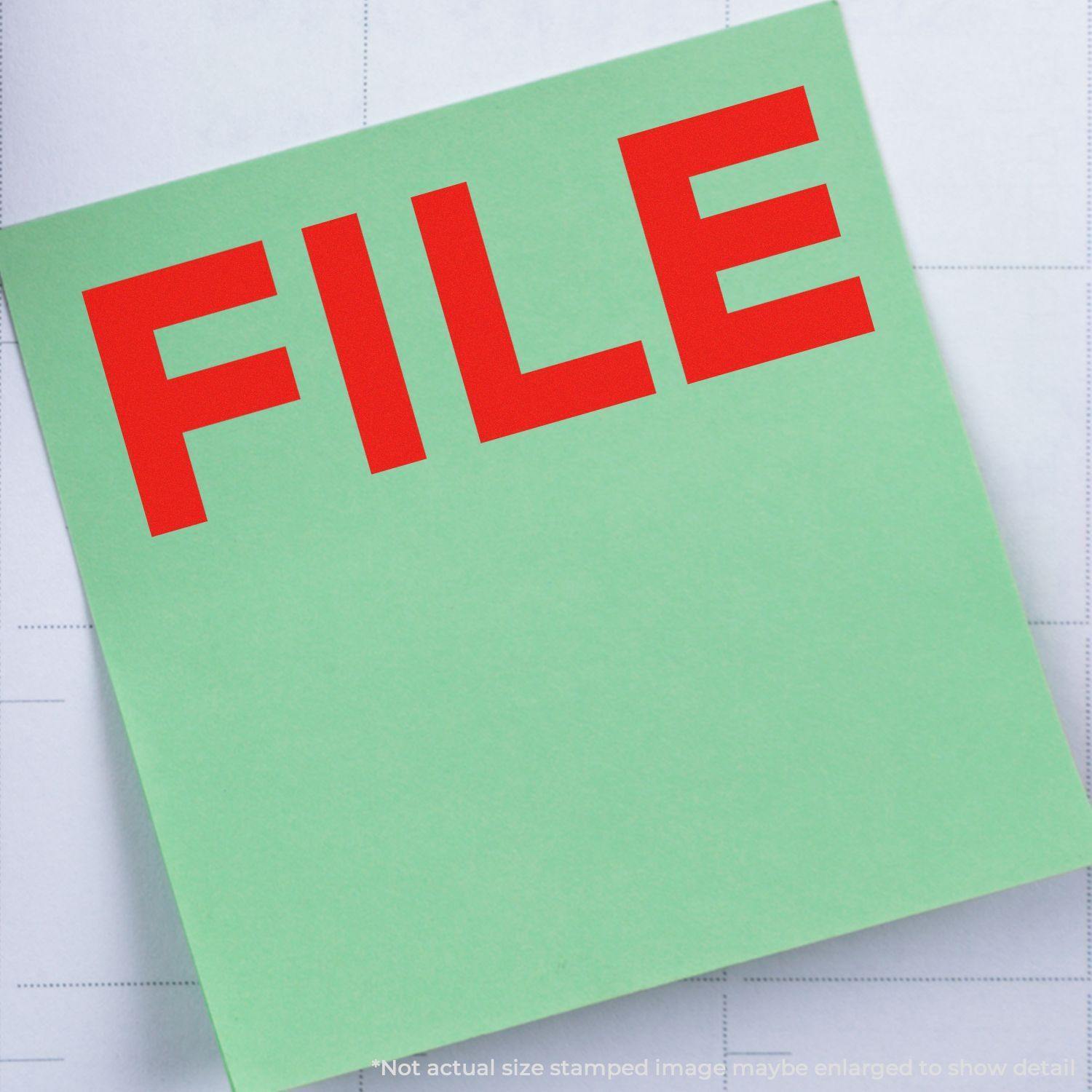 Green paper stamped with a red FILE using a Slim Pre-Inked Bold File Stamp, placed on a grid-lined background.