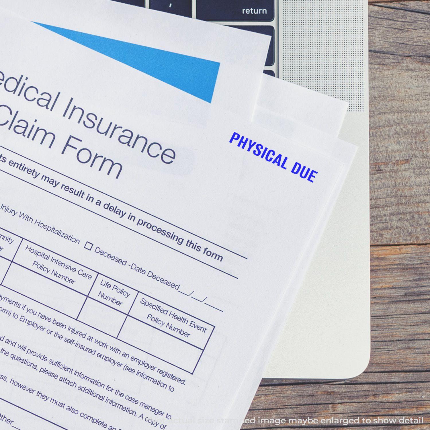 Medical insurance claim form stamped with Large Bold Physical Due Rubber Stamp, placed on a laptop keyboard.