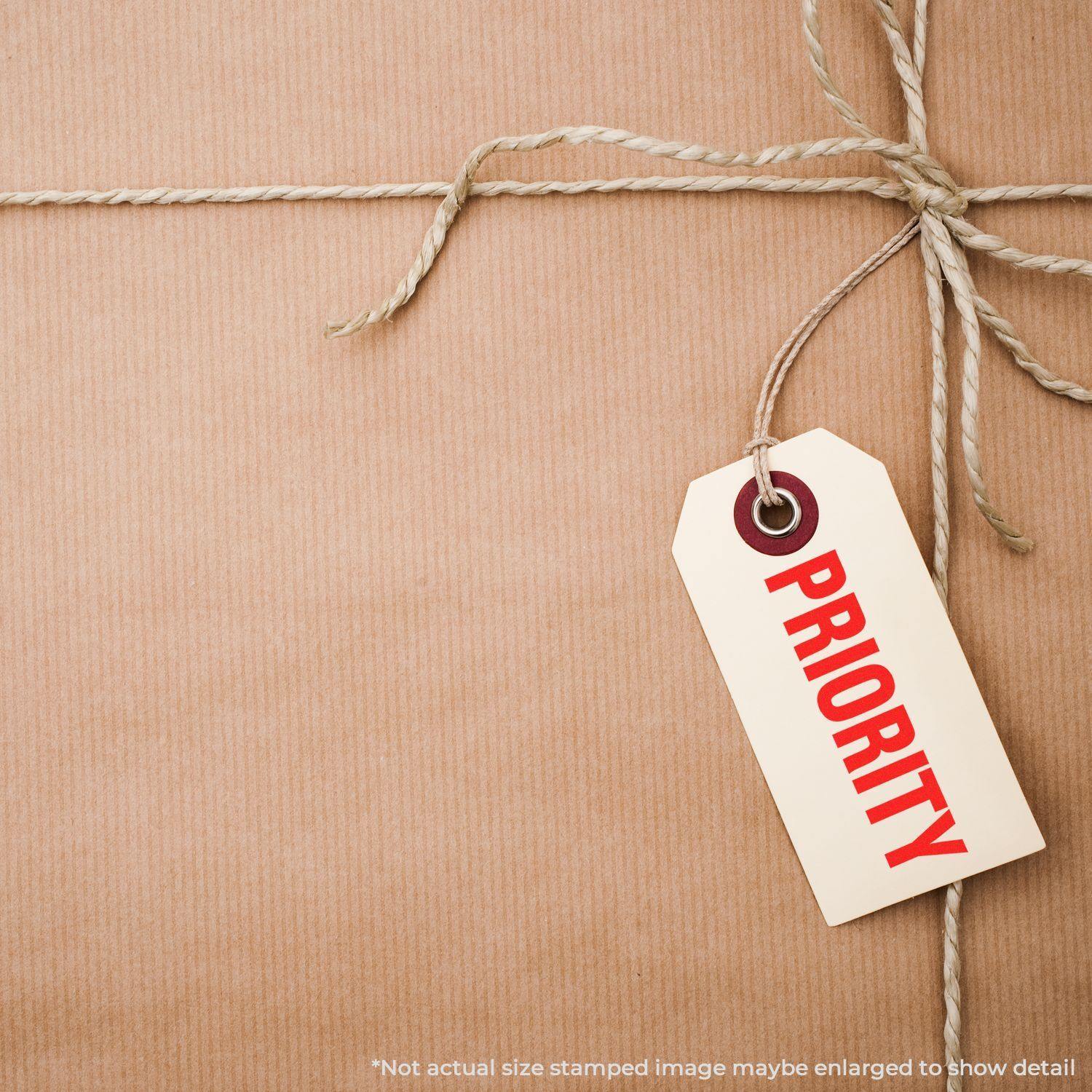 A package wrapped in brown paper and twine with a tag labeled PRIORITY stamped in red using a Bold Priority Rubber Stamp.