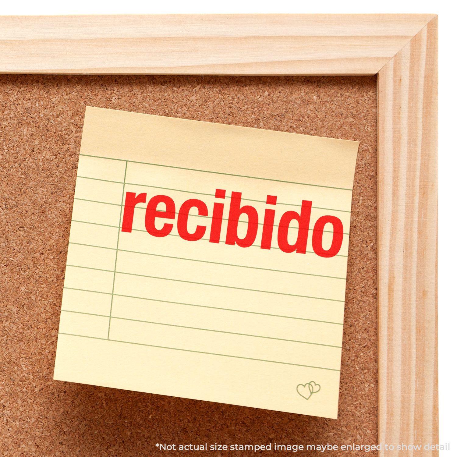 A Slim Pre-Inked Bold Recibido Stamp is used on a yellow sticky note pinned to a corkboard.