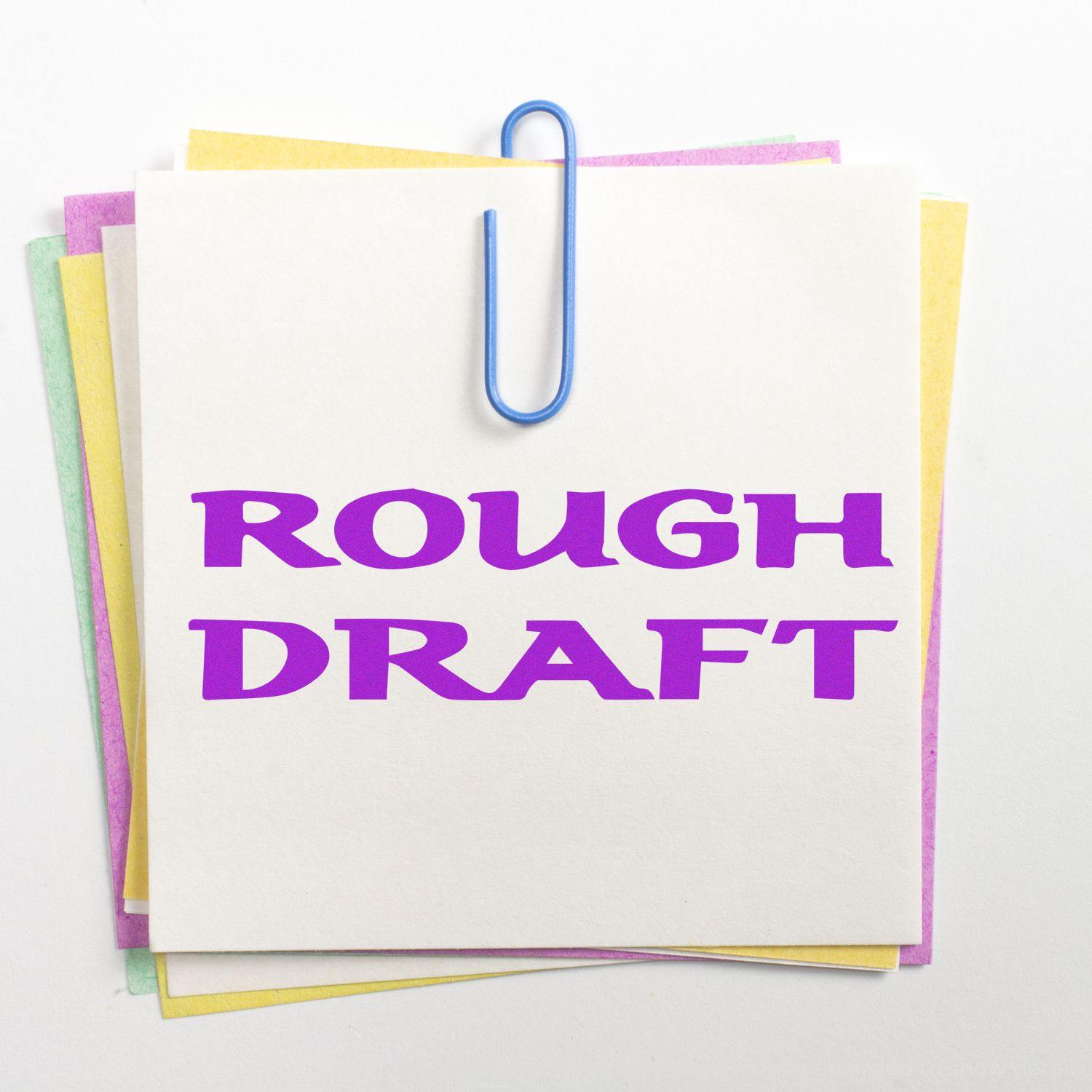 Bold Rough Draft rubber stamp in purple ink on a stack of colorful sticky notes clipped together with a blue paperclip.