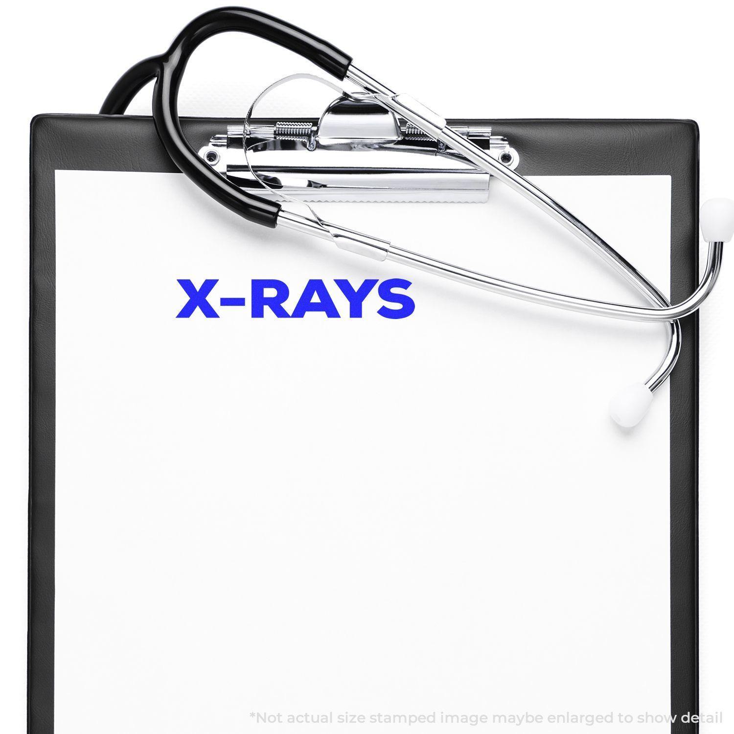 Bold X-Rays Rubber Stamp impression on a clipboard with a stethoscope placed on top.