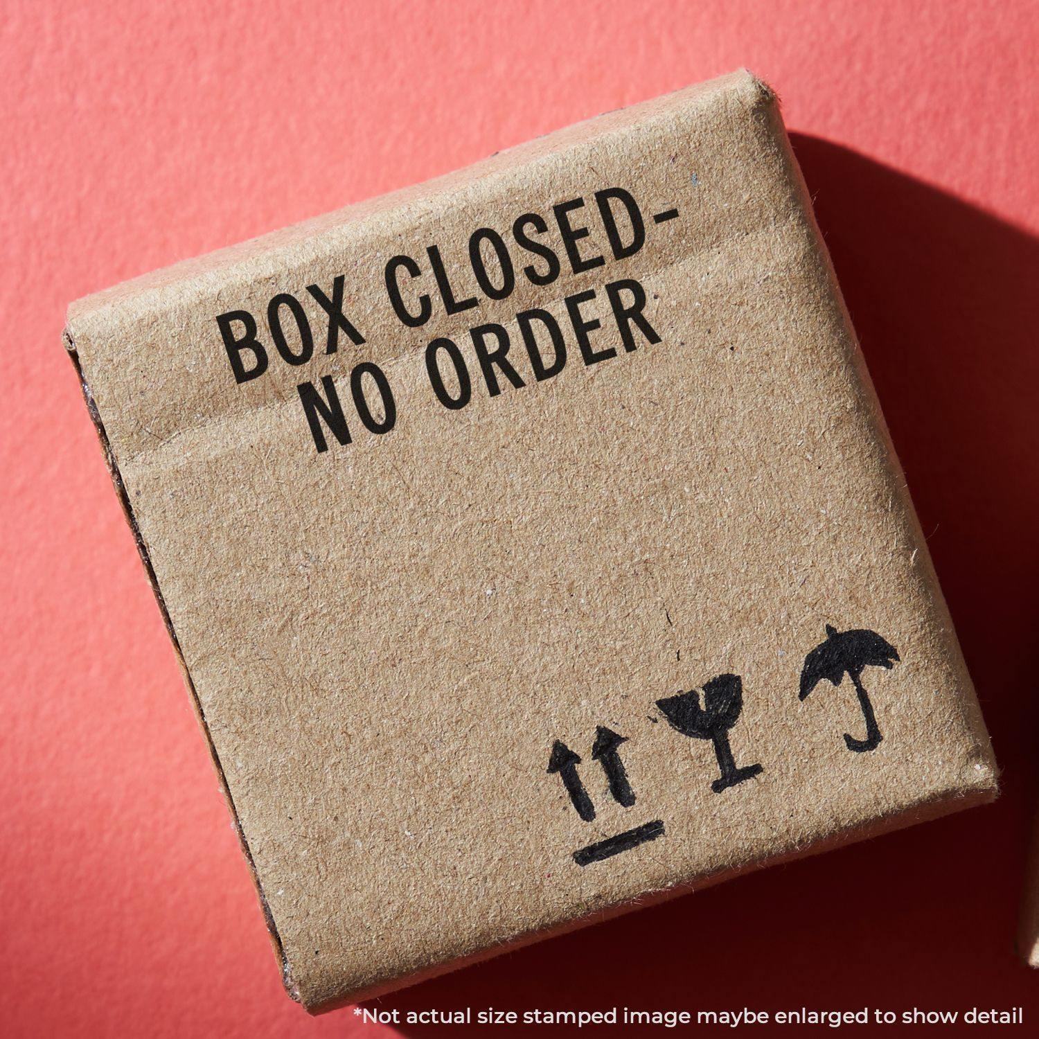 A cardboard box with a Box Closed No Order rubber stamp on it, against a red background.