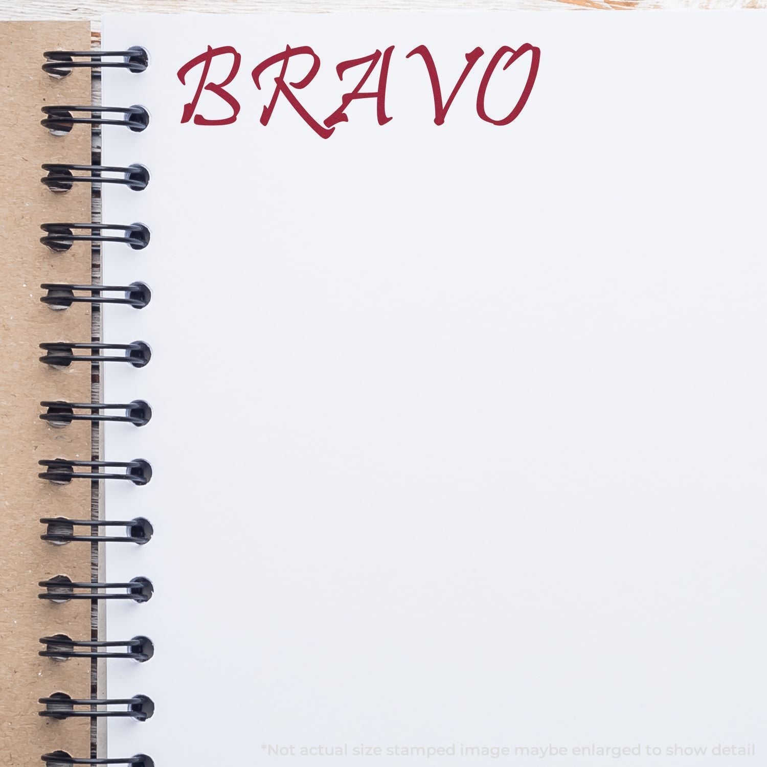 A Self Inking Bravo Stamp imprint on a white notebook page with a brown spiral binding, showing the word BRAVO in red ink.