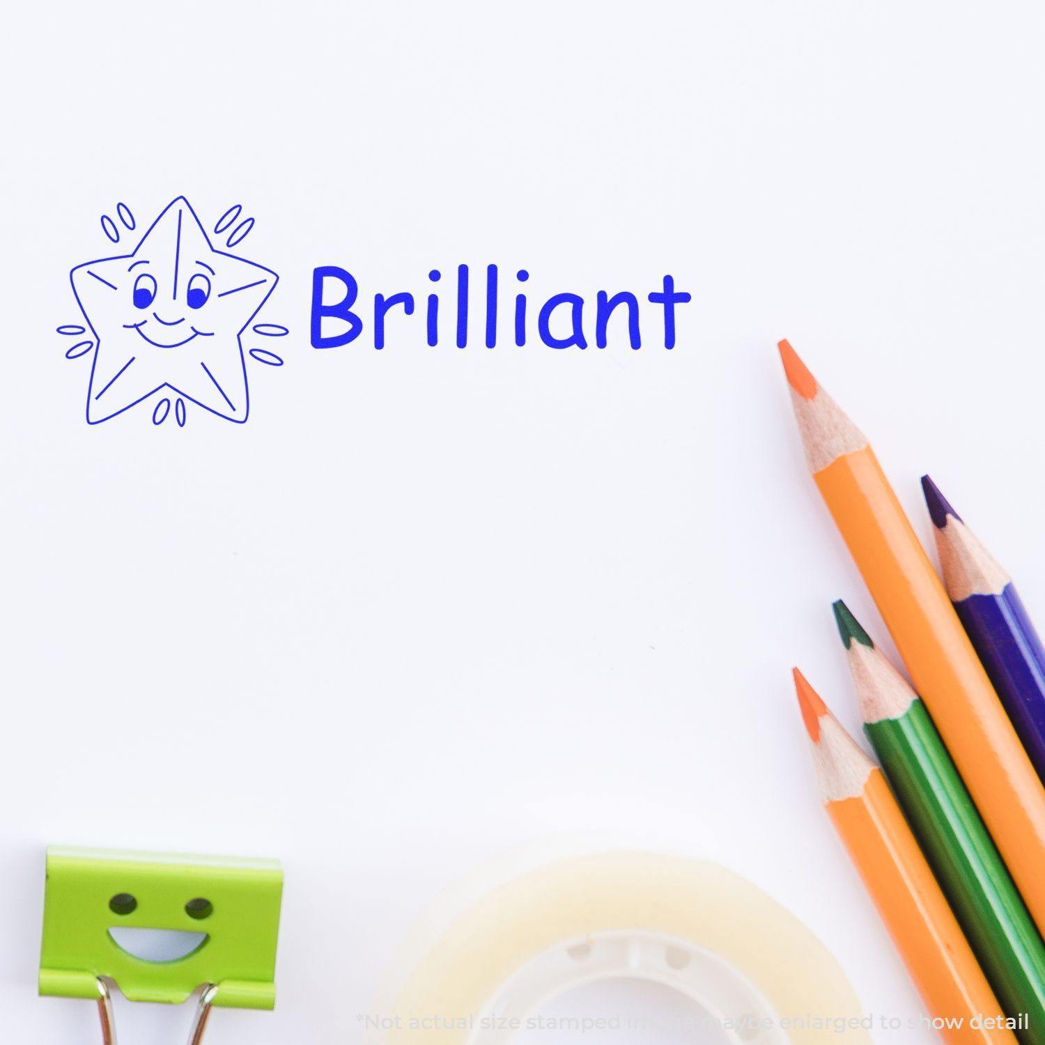 Slim Pre-Inked Brilliant Stamp in blue ink with a smiling star design, next to colorful pencils, a paper clip, and tape.