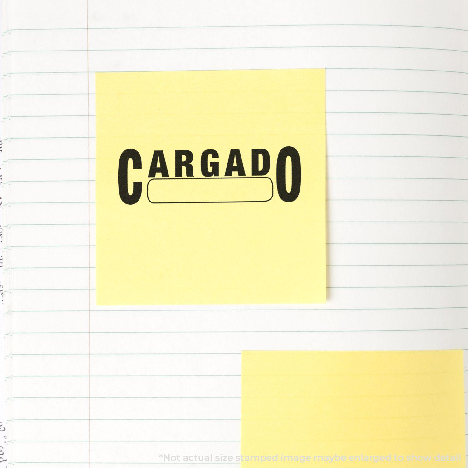 Yellow sticky note stamped with CARGADO using the Self Inking Cargado Stamp on a lined notebook page.