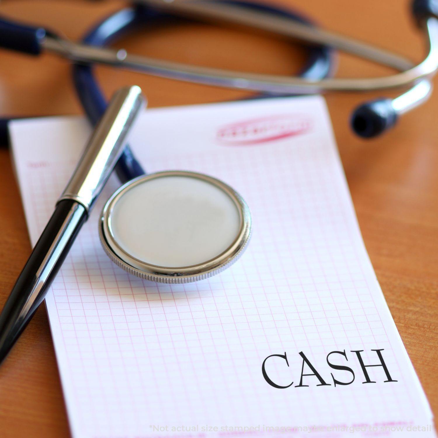 A stethoscope, pen, and paper with CASH stamped using a cash rubber stamp, placed on a wooden desk.