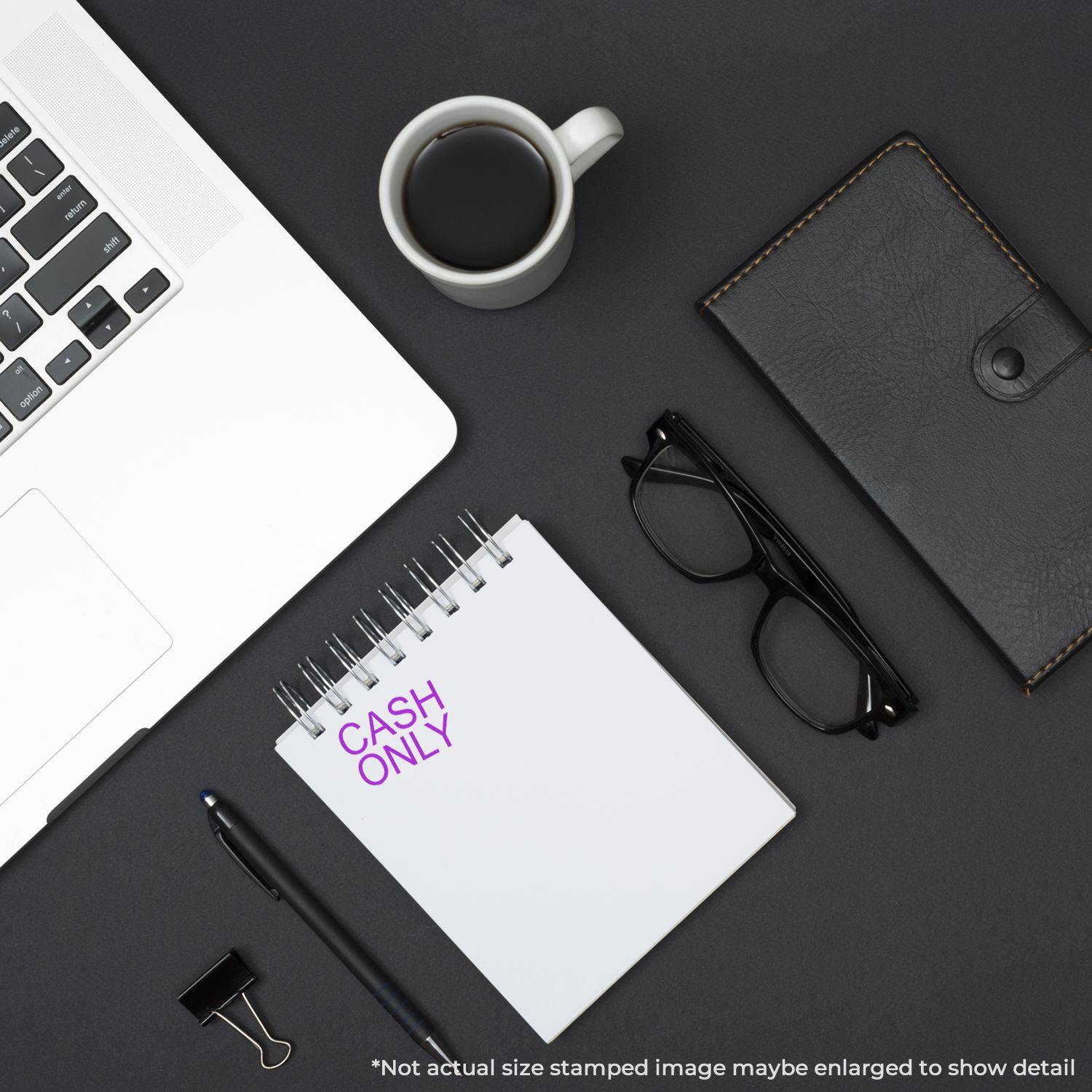 Large Cash Only Rubber Stamp used on a notepad, placed on a desk with a laptop, coffee cup, glasses, wallet, and a binder clip.