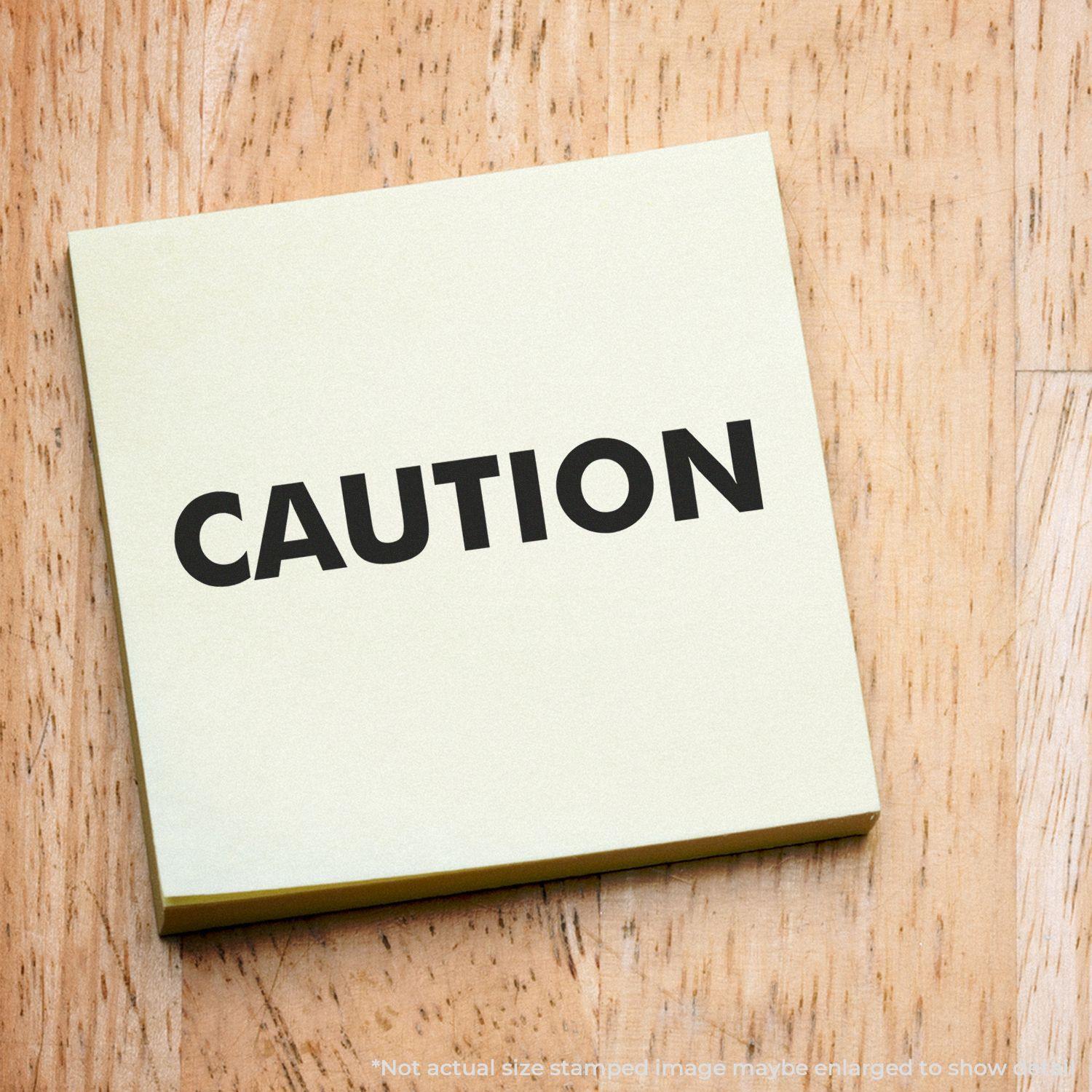 Caution Rubber Stamp on a yellow sticky note placed on a wooden surface. The word CAUTION is clearly visible in bold black letters.