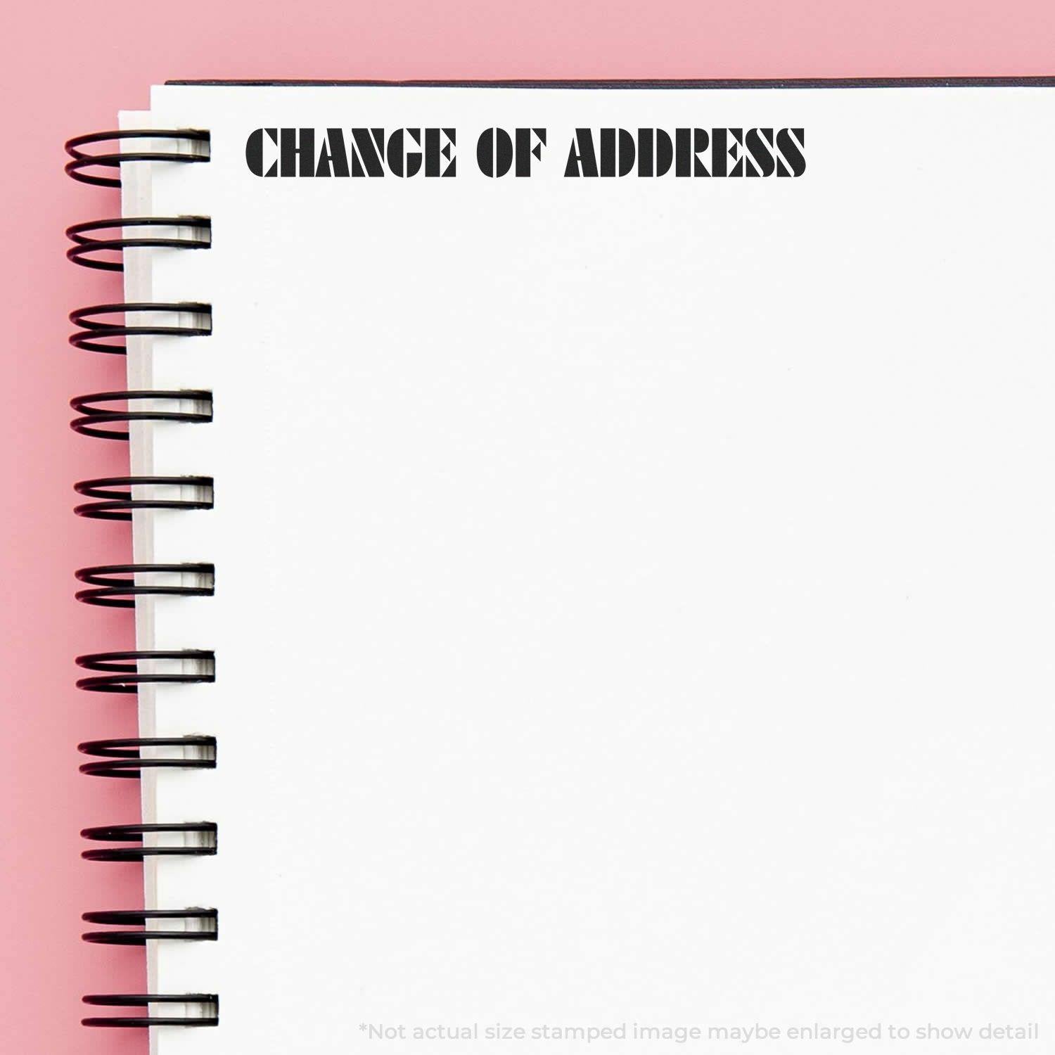 Change Of Address Rubber Stamp used on a spiral notebook with a pink background. The text 'CHANGE OF ADDRESS' is stamped in bold, black letters.