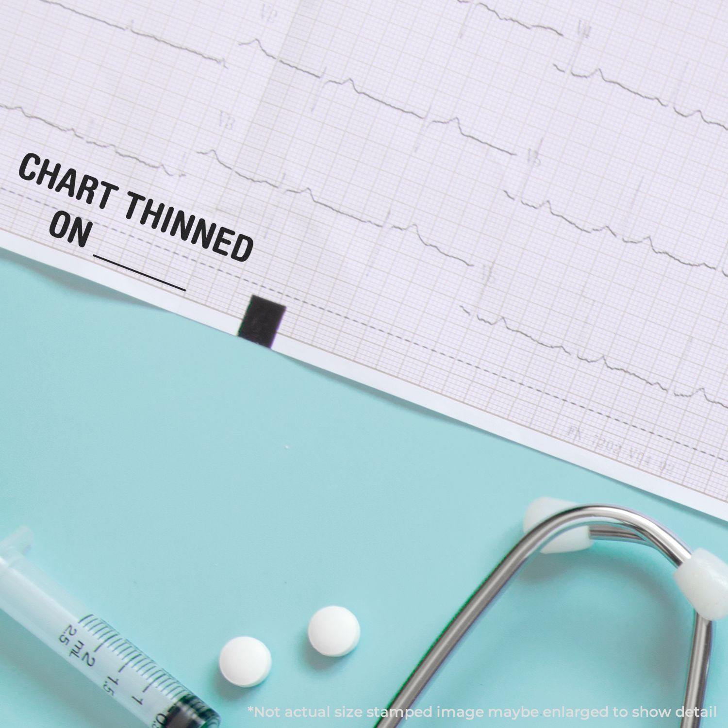 Image of a medical chart stamped with 'Chart Thinned On' using the Large Self Inking Chart Thinned On Stamp, alongside a stethoscope, syringe, and white pills on a light blue surface.