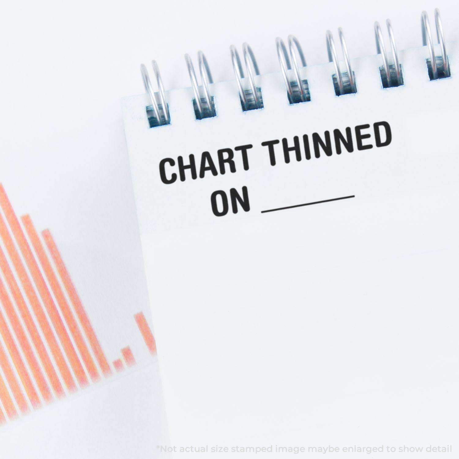 Spiral notebook with 'Chart Thinned On' rubber stamp text and a blank line, next to a graph with orange bars on the left.