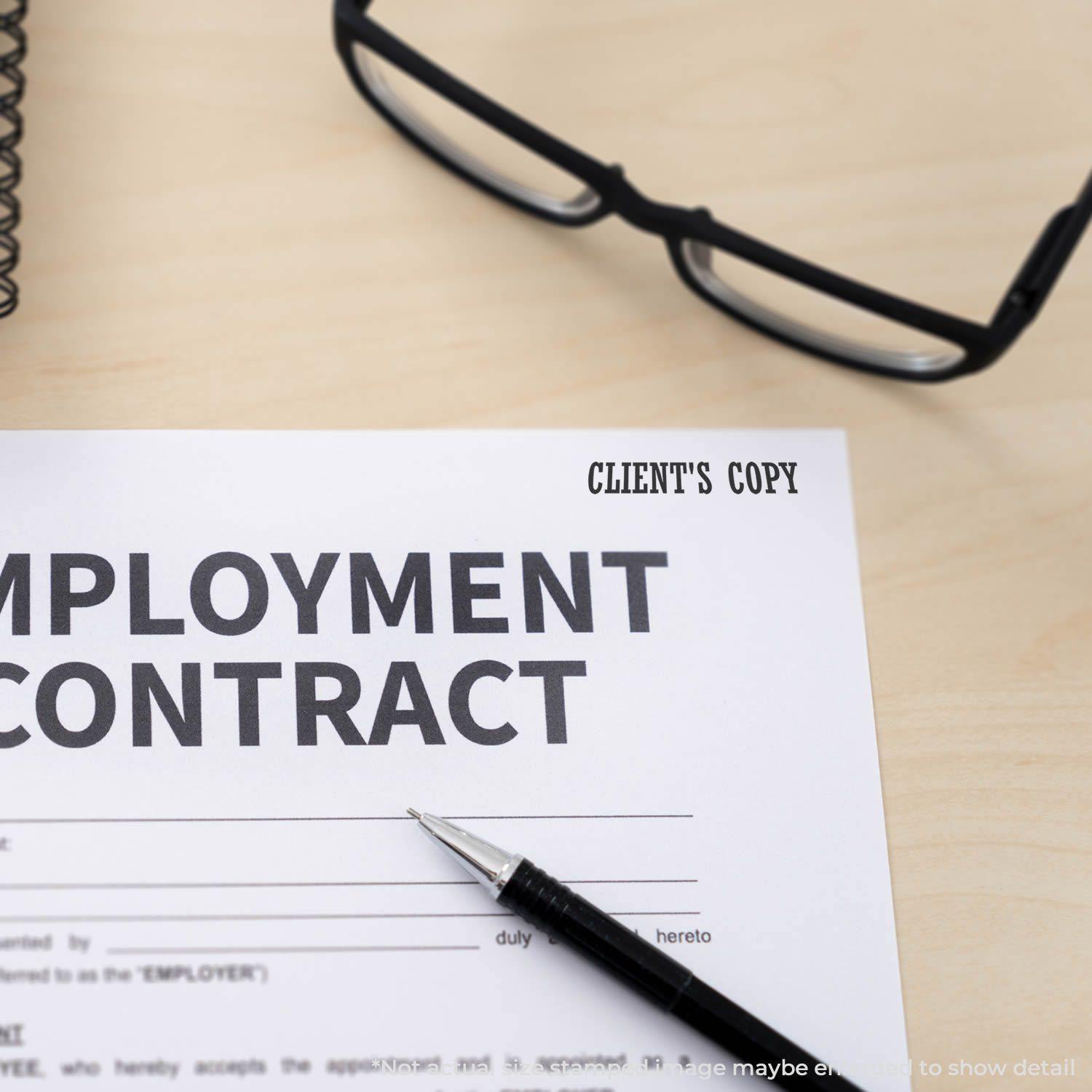 Self Inking Clients Copy Stamp marking an employment contract on a desk with glasses and a pen nearby.