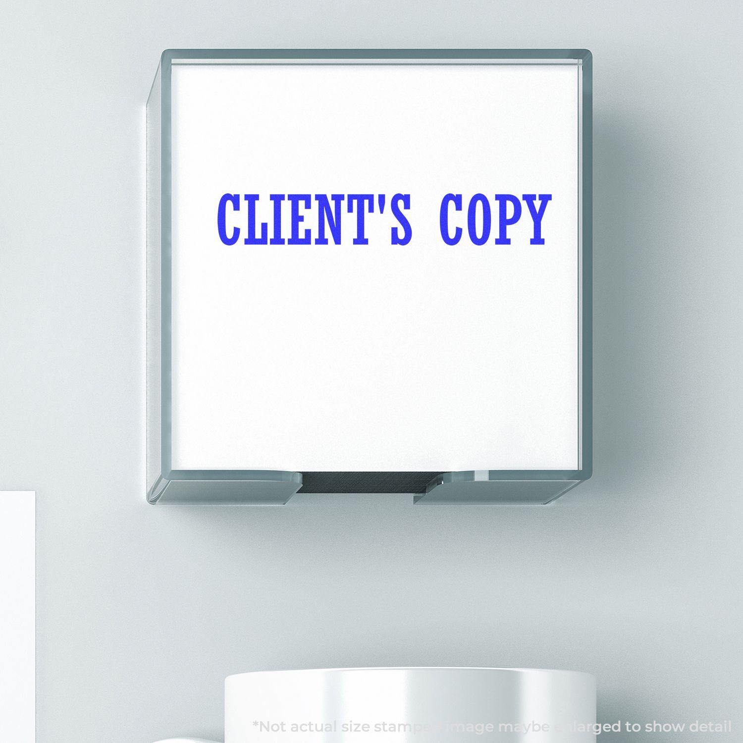 Image of a Client's Copy rubber stamp with blue text on a white background, mounted on a wall above a white surface.