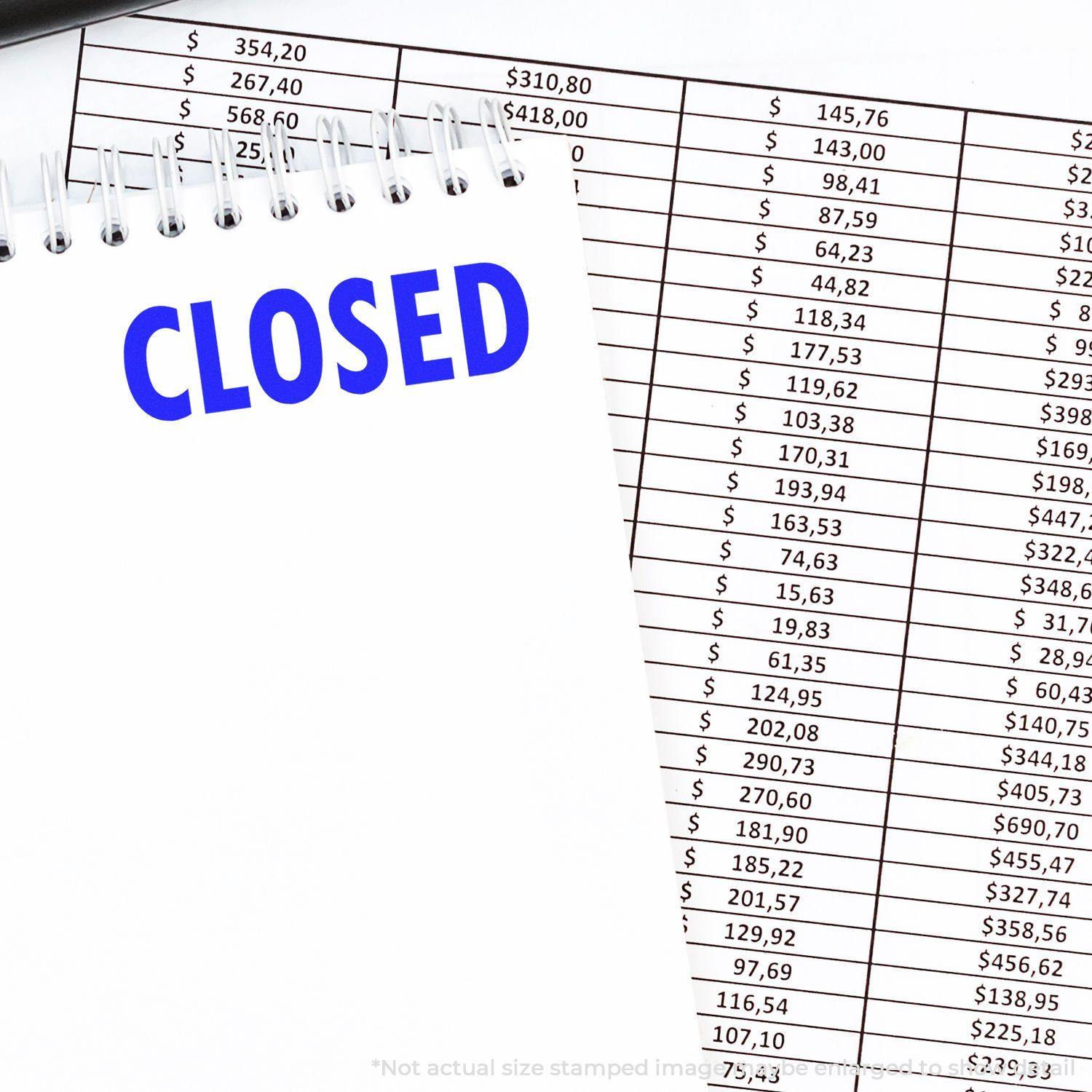 Slim Pre-Inked Closed Stamp on a notepad with CLOSED text, placed over financial documents with numerical data.