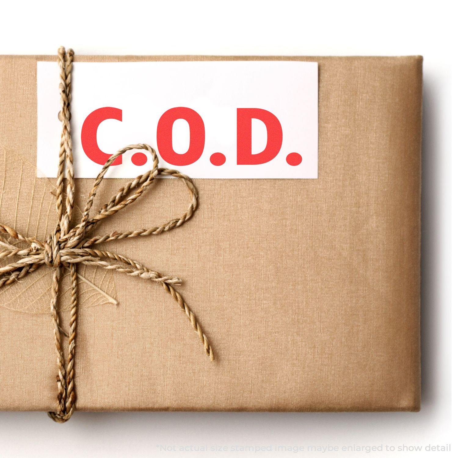 A brown package with a C.O.D. label stamped using the Large Self Inking COD Office Stamp, tied with a twine bow.