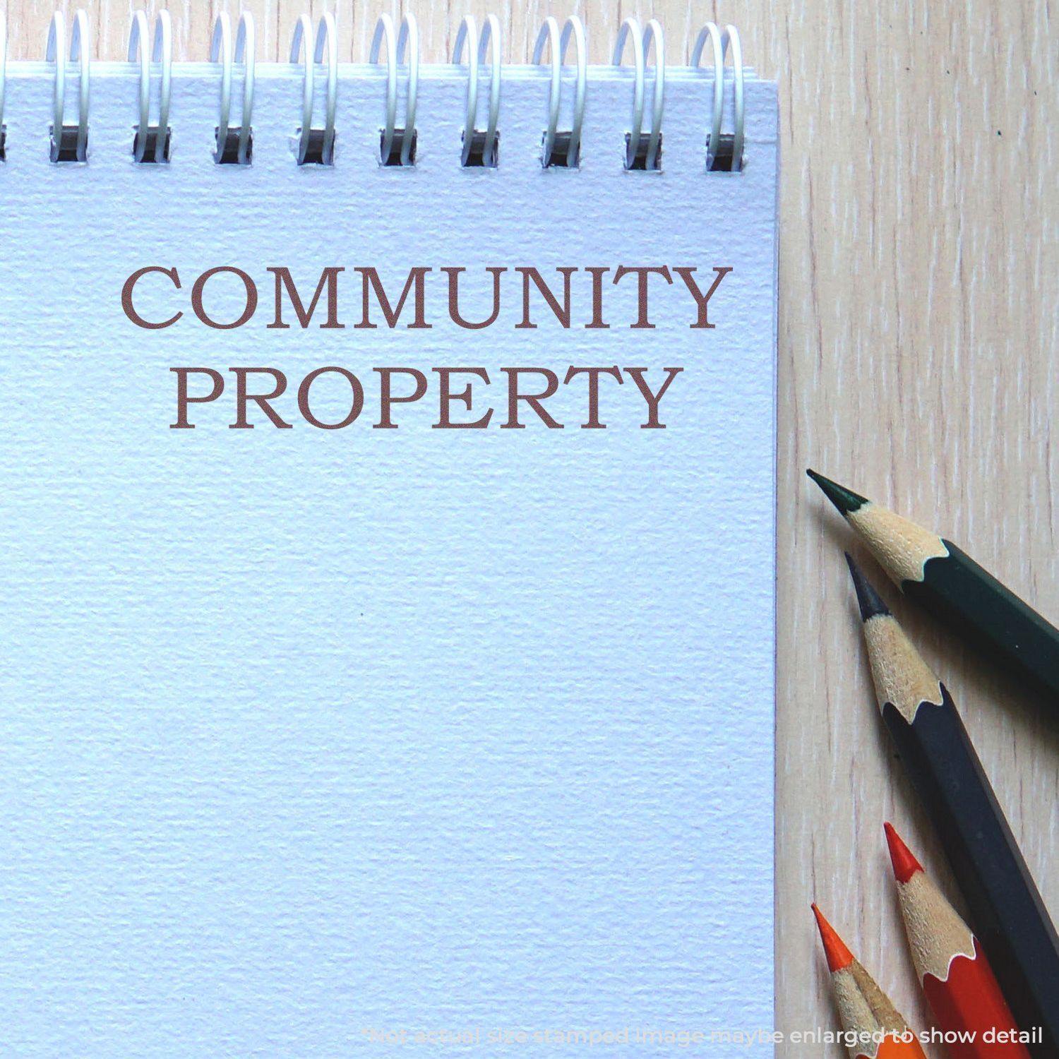 A self-inking stamp with a stamped image showing how the text "COMMUNITY PROPERTY" in a large bold font is displayed by it.