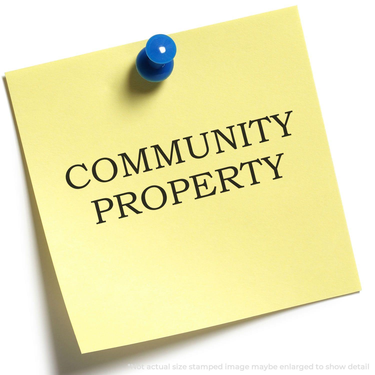 Yellow sticky note with COMMUNITY PROPERTY stamped on it using the Large Community Property Rubber Stamp, pinned with a blue pushpin.