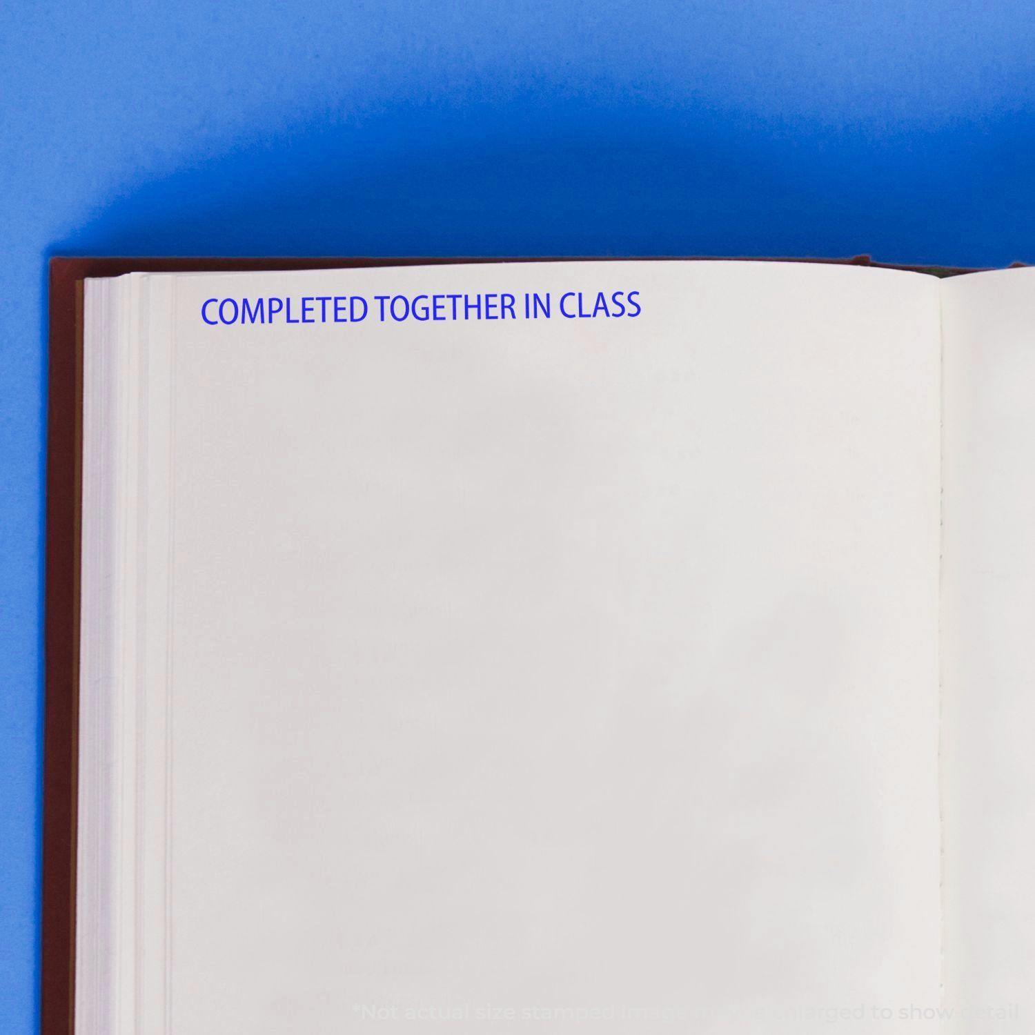 Completed Together In Class Rubber Stamp used on a blank page of an open book with a blue background.