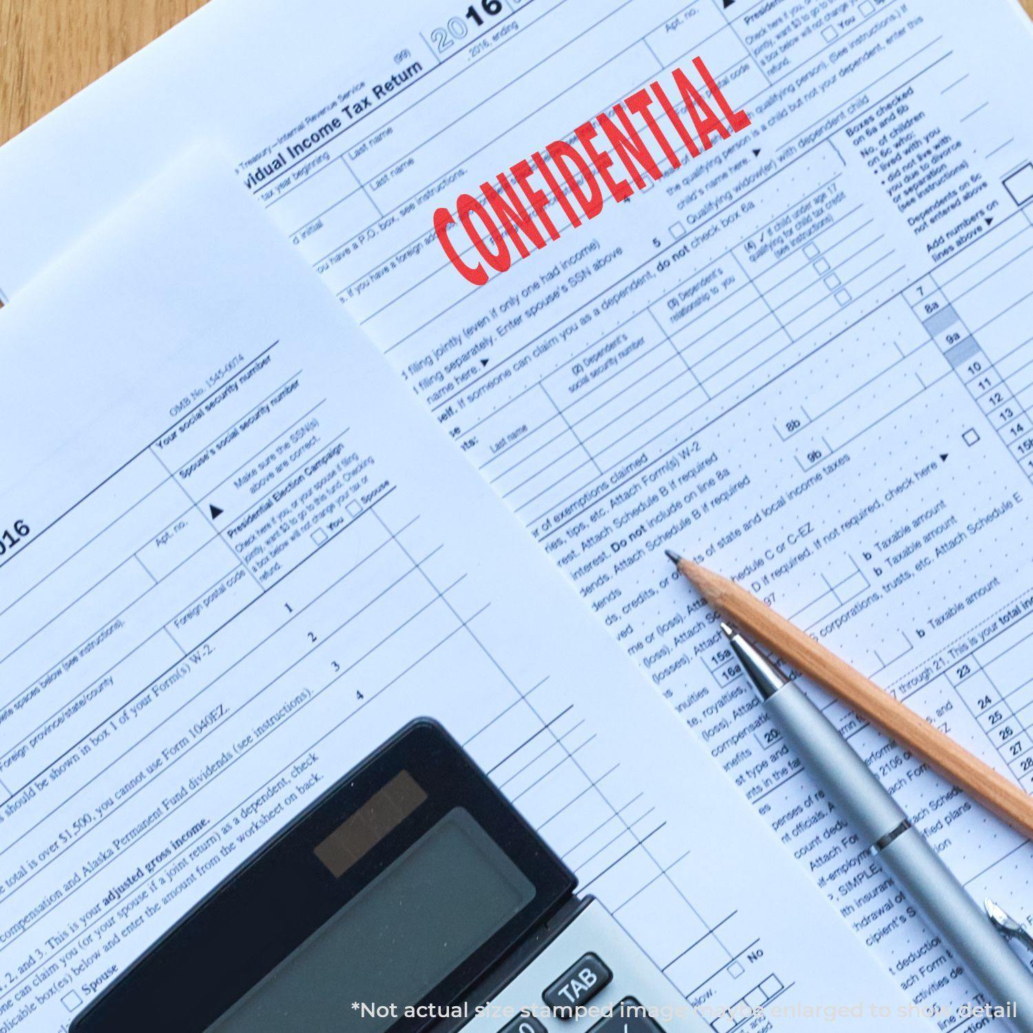 Slim Pre-Inked Confidential Stamp marking CONFIDENTIAL in red on tax documents, with a calculator and pencil nearby.