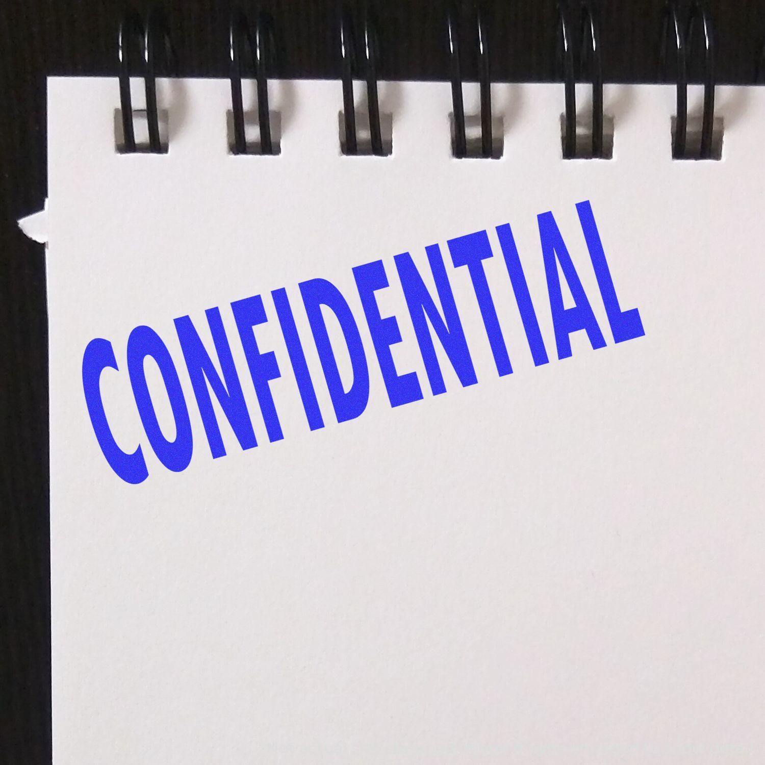 A notebook page stamped with a blue CONFIDENTIAL using the Confidential Rubber Stamp, with a black spiral binding at the top.