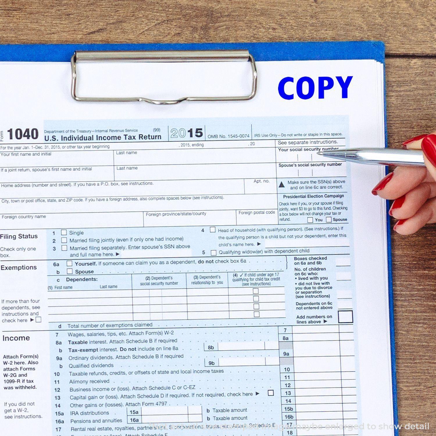 A hand holding a pen points to a U.S. tax form on a clipboard with a Slim Pre-Inked Copy Stamp marking the word COPY in blue.