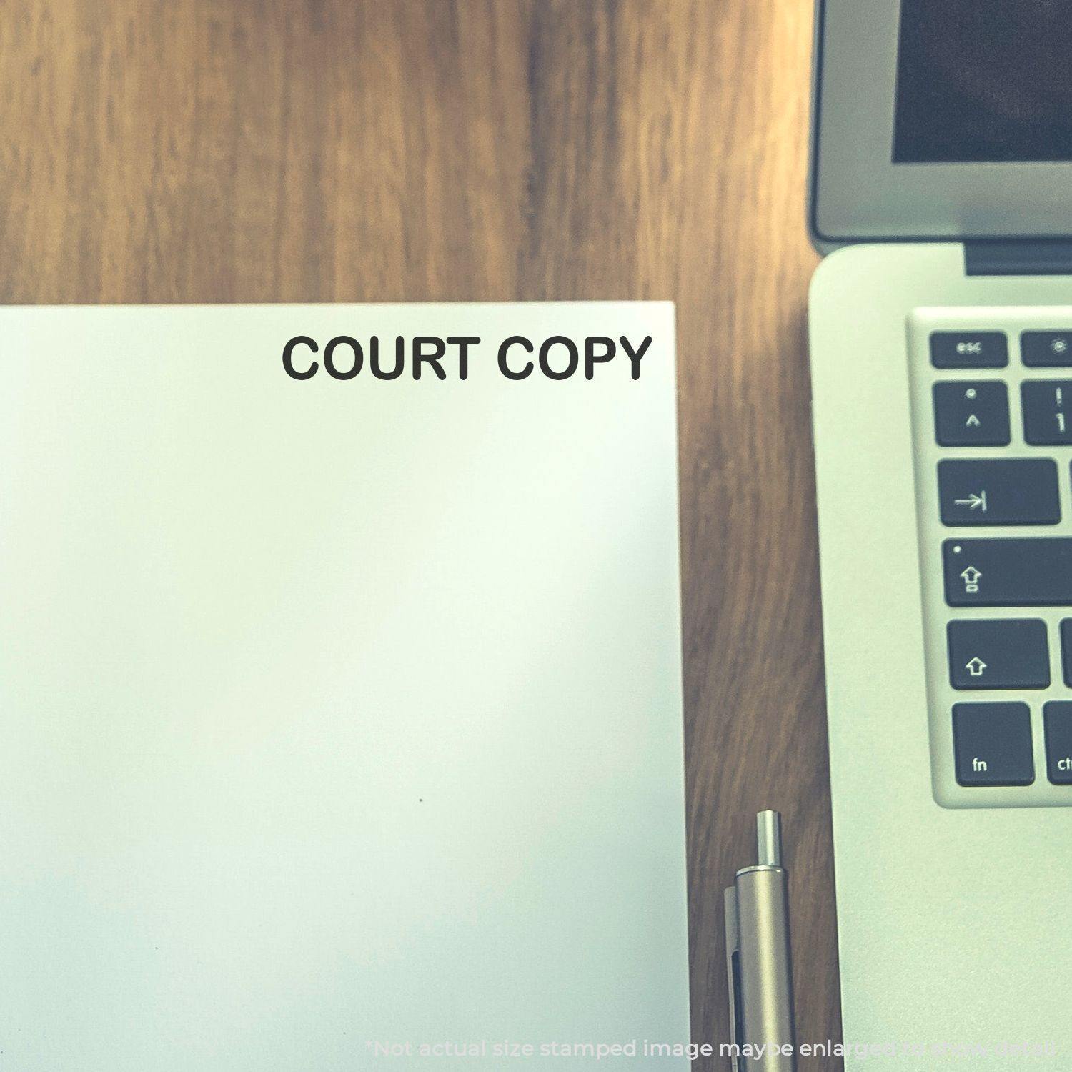 A document stamped with COURT COPY using the Court Copy Rubber Stamp, placed next to a laptop and pen on a wooden desk.