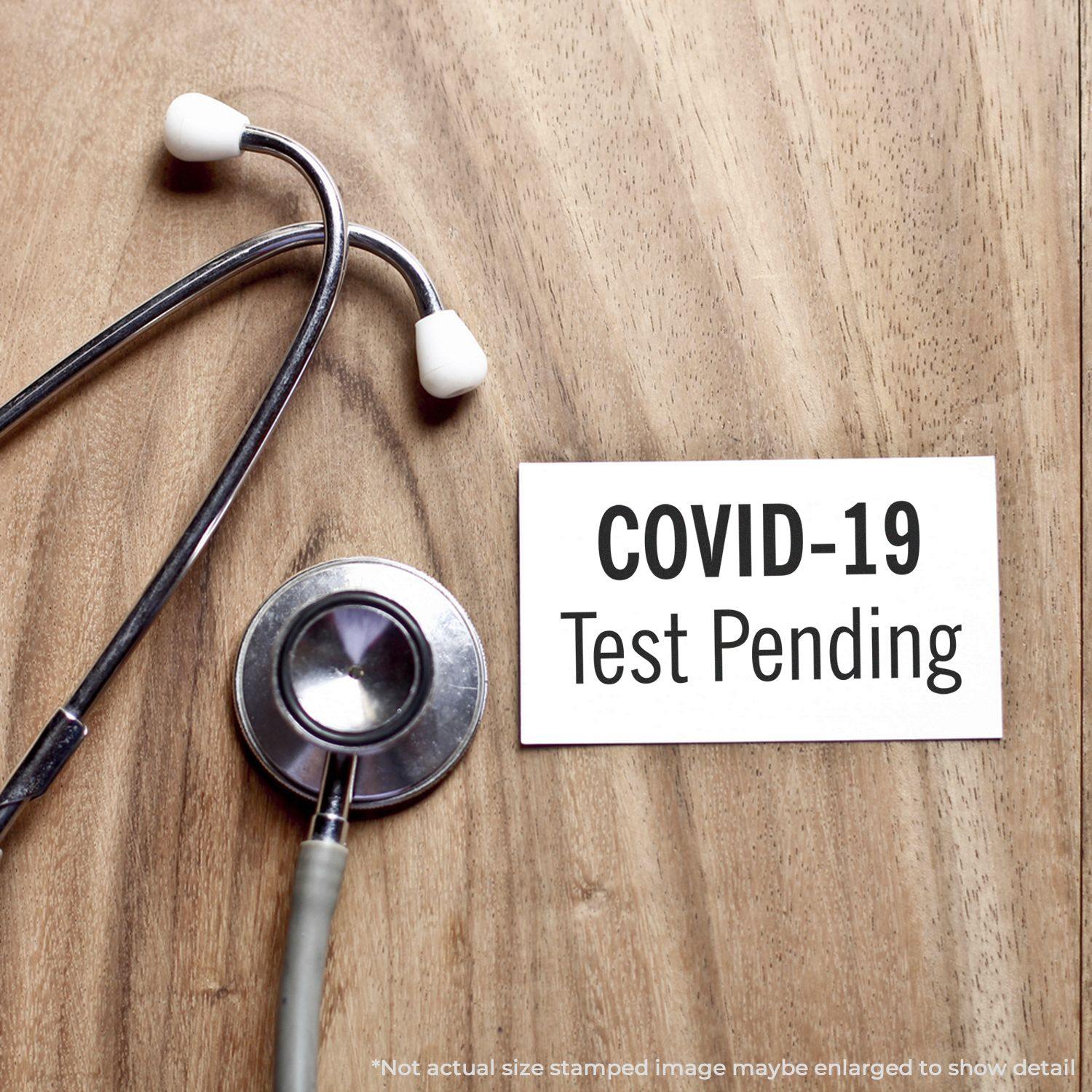 Stethoscope on wooden surface next to a card stamped with COVID-19 Test Pending using a Slim Pre-Inked Covid-19 Test Pending Stamp.