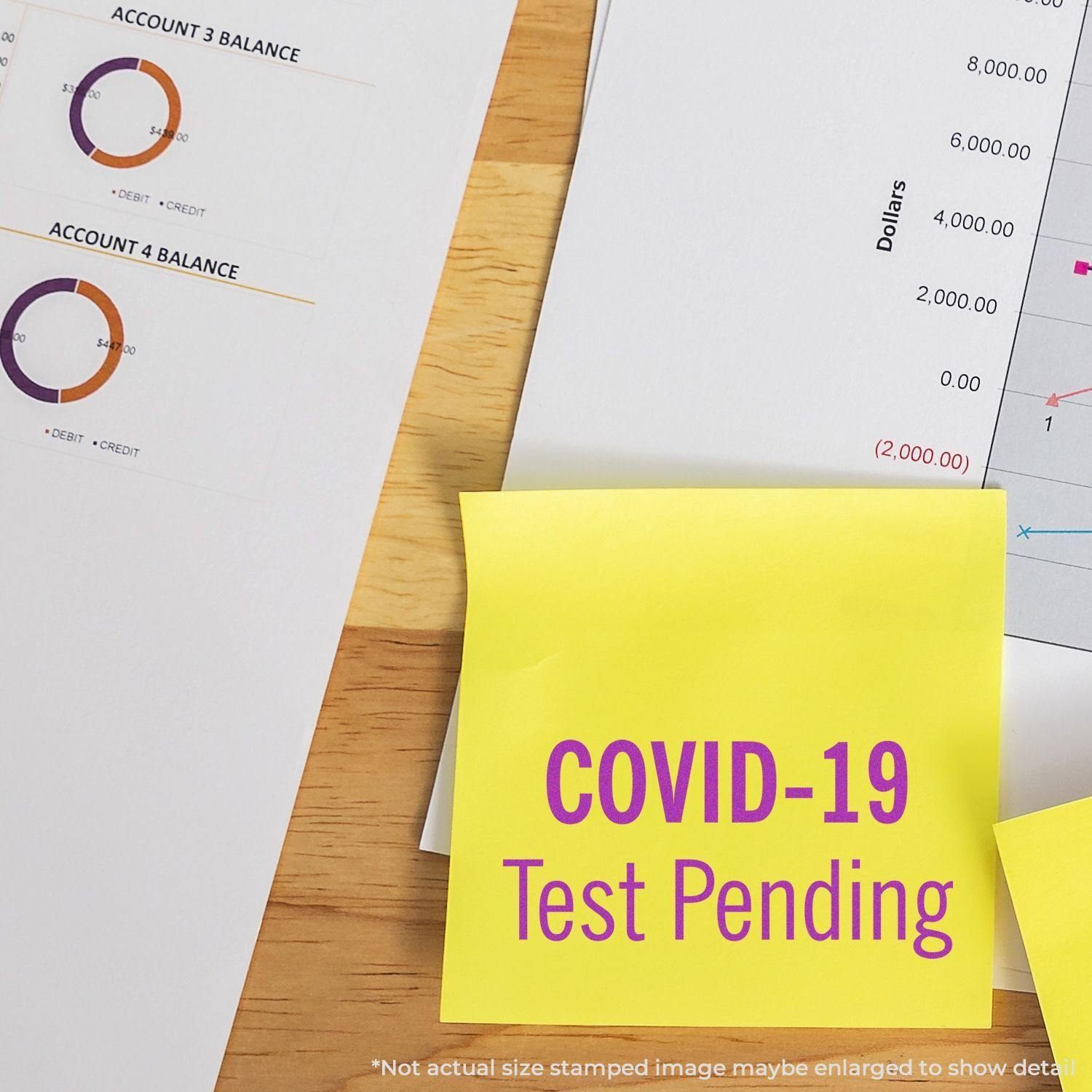 Self Inking Covid-19 Test Pending Stamp on a yellow sticky note, placed on a desk with financial documents and charts.