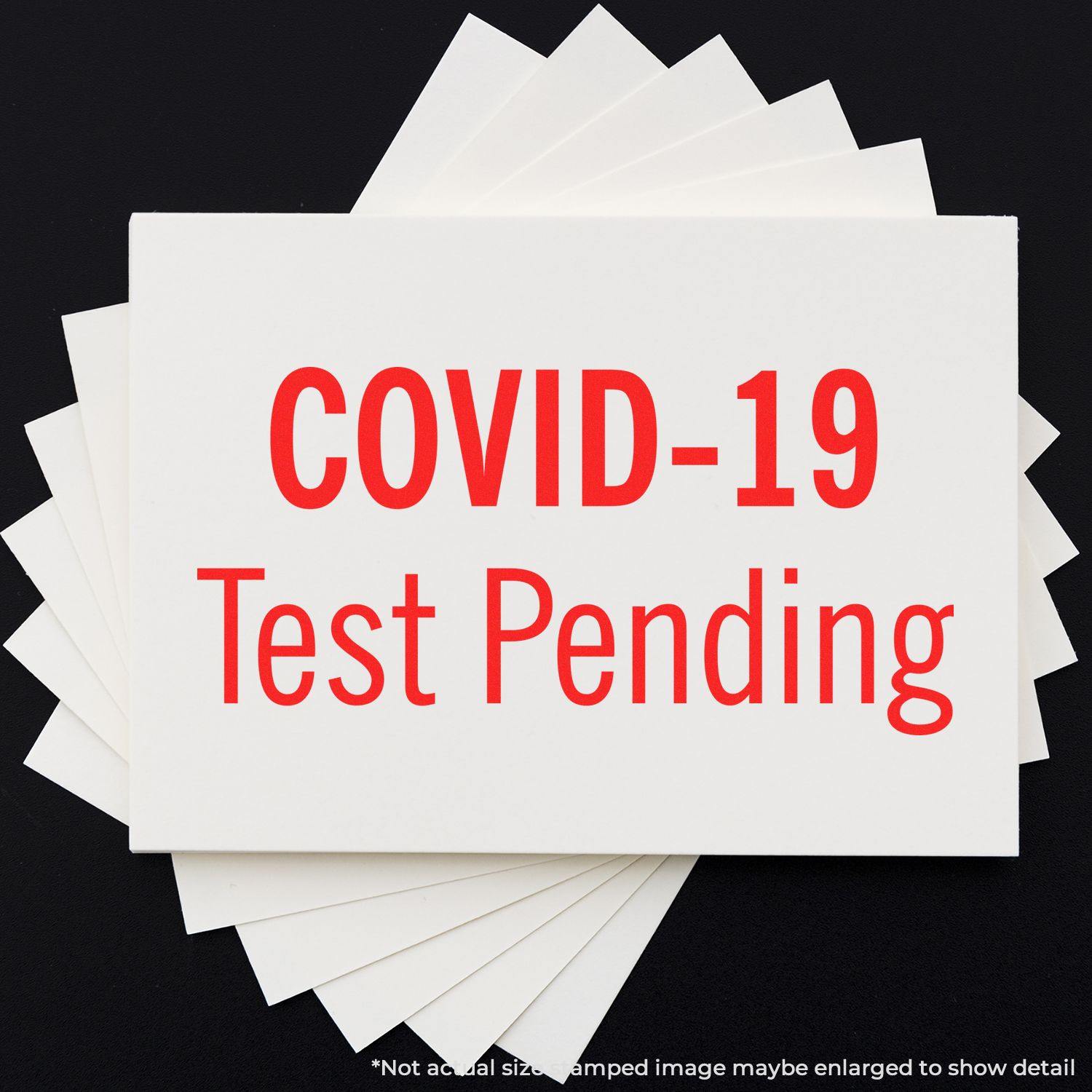 Large Covid-19 Test Pending Rubber Stamp in red ink on white cards, indicating test results are pending. Cards are fanned out on a black surface.