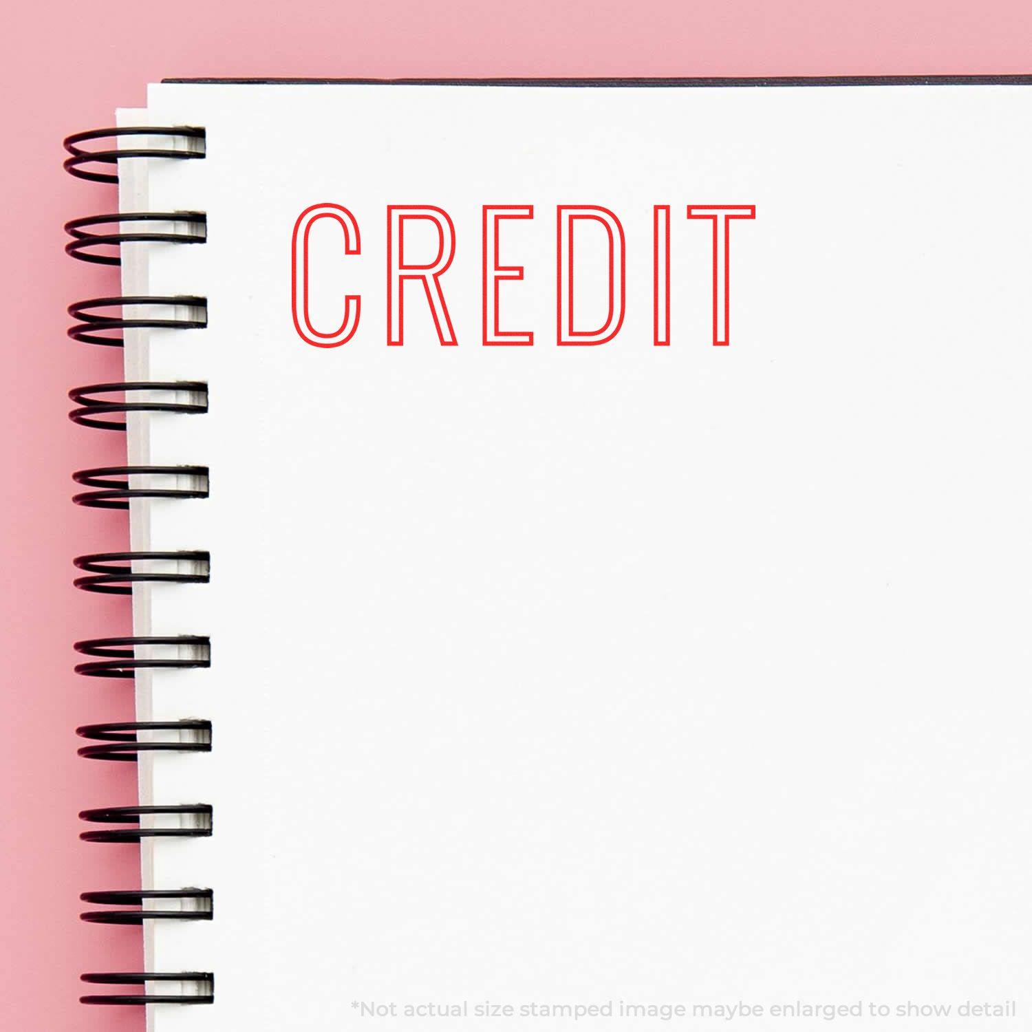 Notebook with 'CREDIT' stamped in red using a Slim Pre-Inked Credit Outline Stamp on a white page with a pink background.