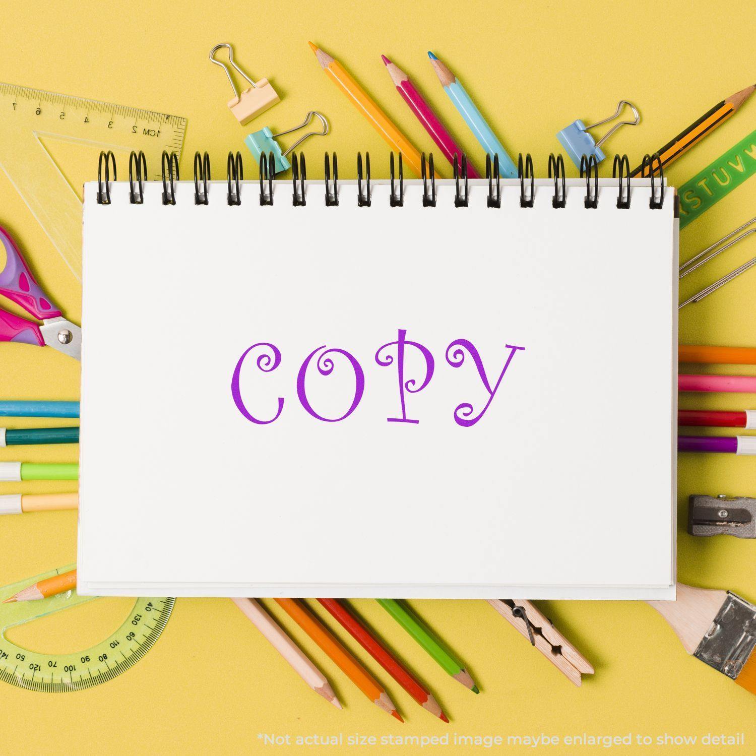 Self Inking Curly Copy Stamp used on a white notebook page surrounded by colorful stationery on a yellow background.